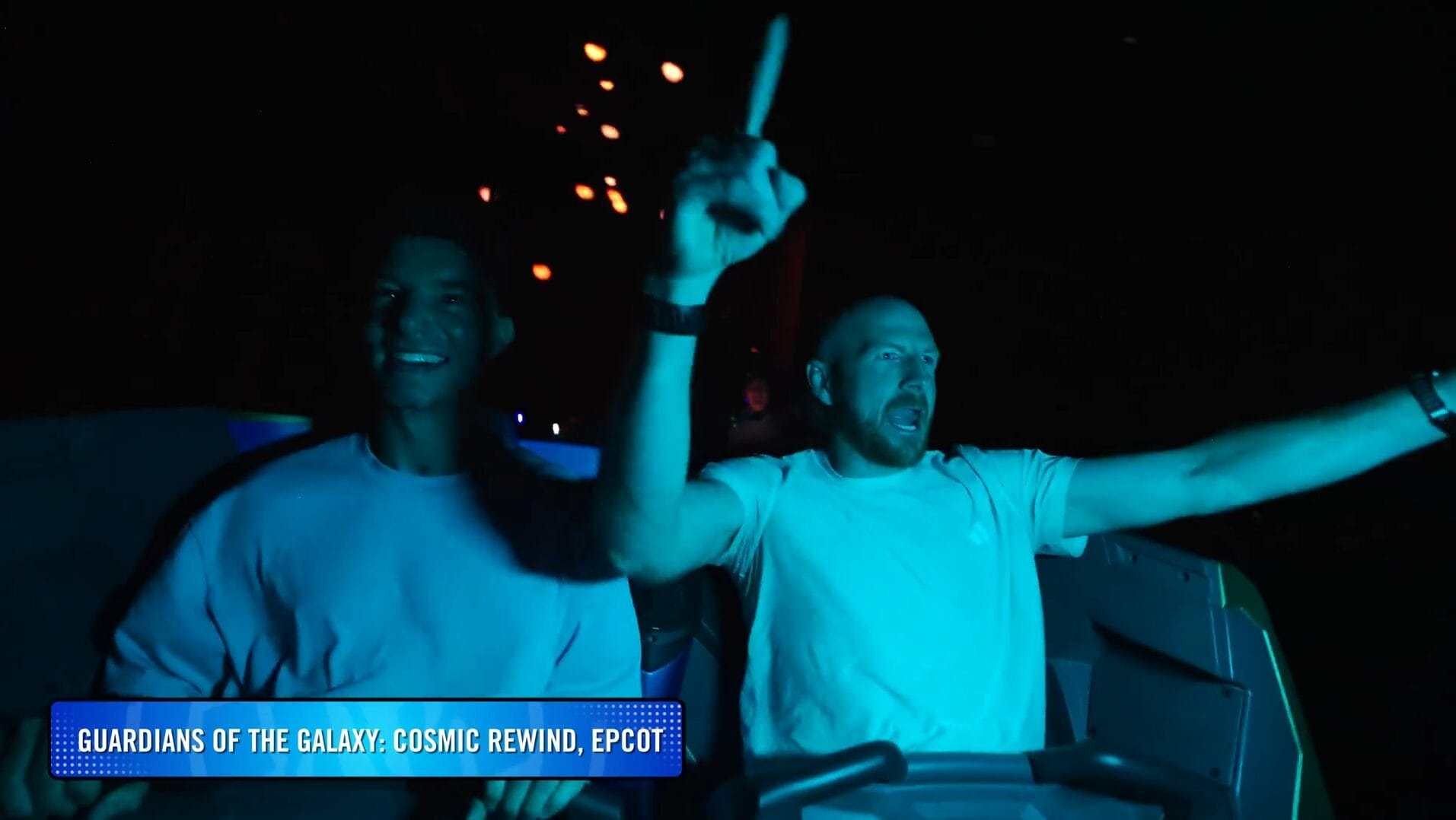 Two people, lit by blue lights, excitedly ride Guardians of the Galaxy: Cosmic Rewind at Disney Park.