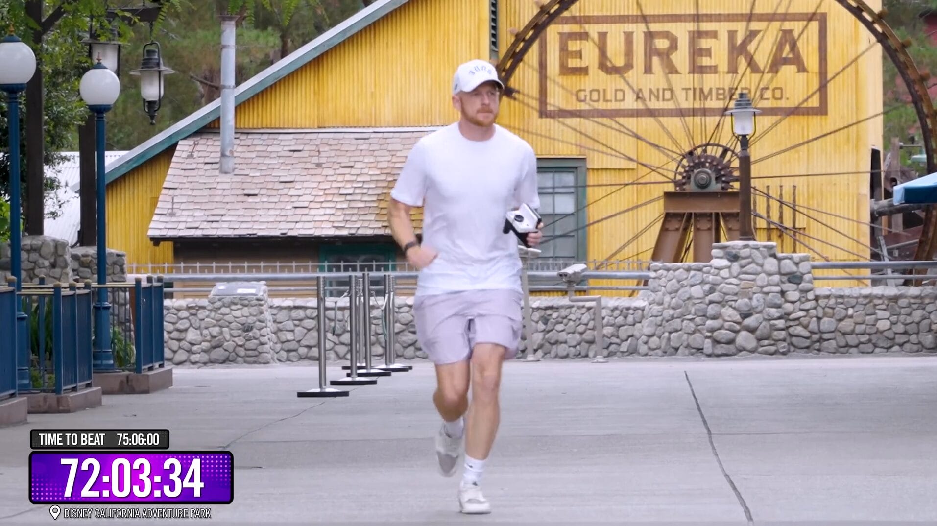 Man in white shirt and shorts runs outside a Disney Park near “Eureka Gold and Timber” as VIDEO timer reads 72:03.41.