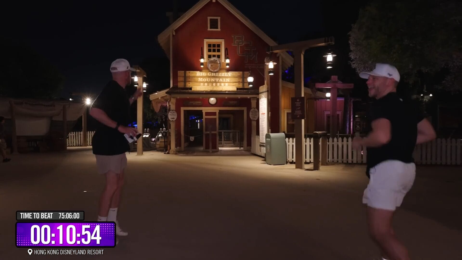 Two men in shorts and caps stand before Big Grizzly Mountain at night in a Dude Perfect Disney Park video, timer on screen.