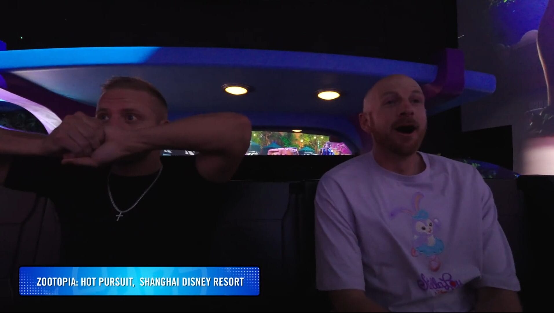 Two men sit in a ride vehicle at Disney Park, appearing excited as if filming a Dude Perfect video.