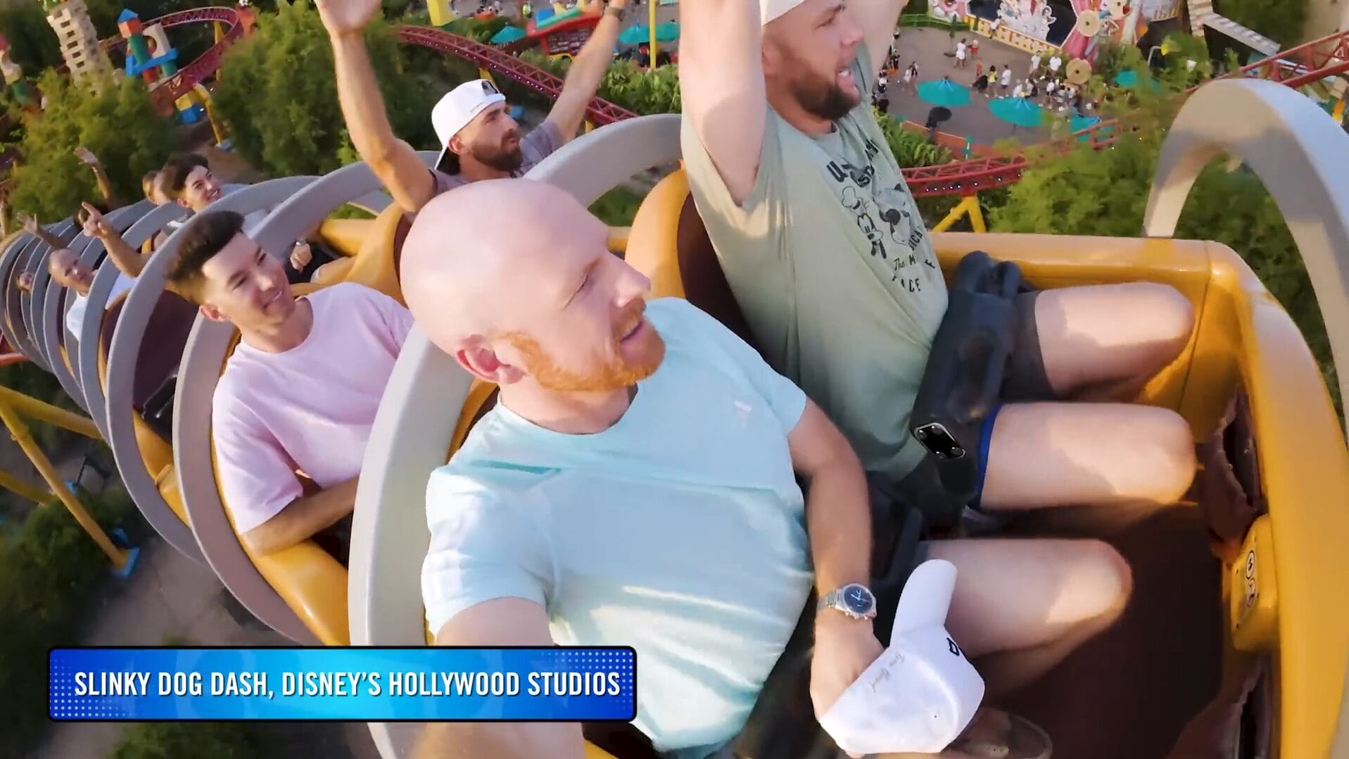 Four adults ride the Slinky Dog Dash roller coaster at Disney Park, raising their hands in excitement—perfect for a VIDEO!