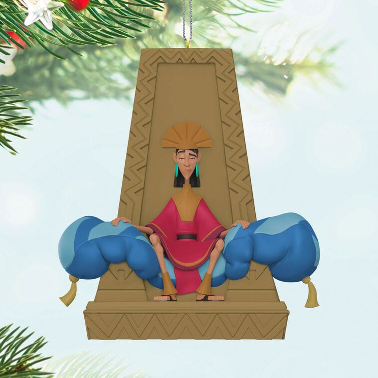 Hallmark ornament of a cartoon emperor in red and gold robes on a throne, hanging from a tree, similar to Disney Park decor.