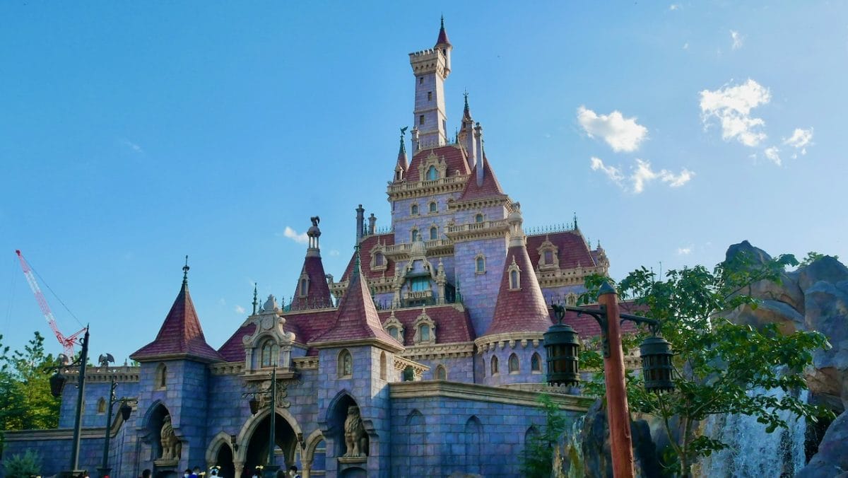 A grand castle with red roofs and tall spires at Epic Universe, resembling but distinct from Disneyland and Disney World castles.