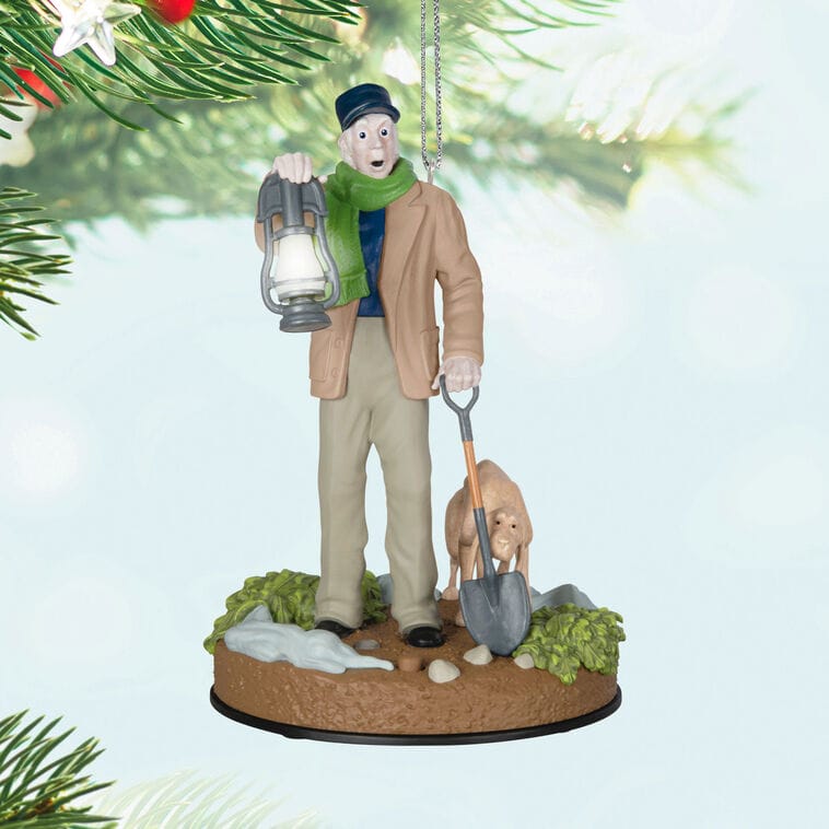 Hallmark Christmas ornament of an older man with lantern, shovel, and dog digging, hanging from a tree—no Disney castle in sight.