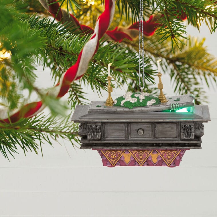 Christmas tree branch with a Hallmark ornament shaped like a church altar, candles, and green details—not a Disney park castle.