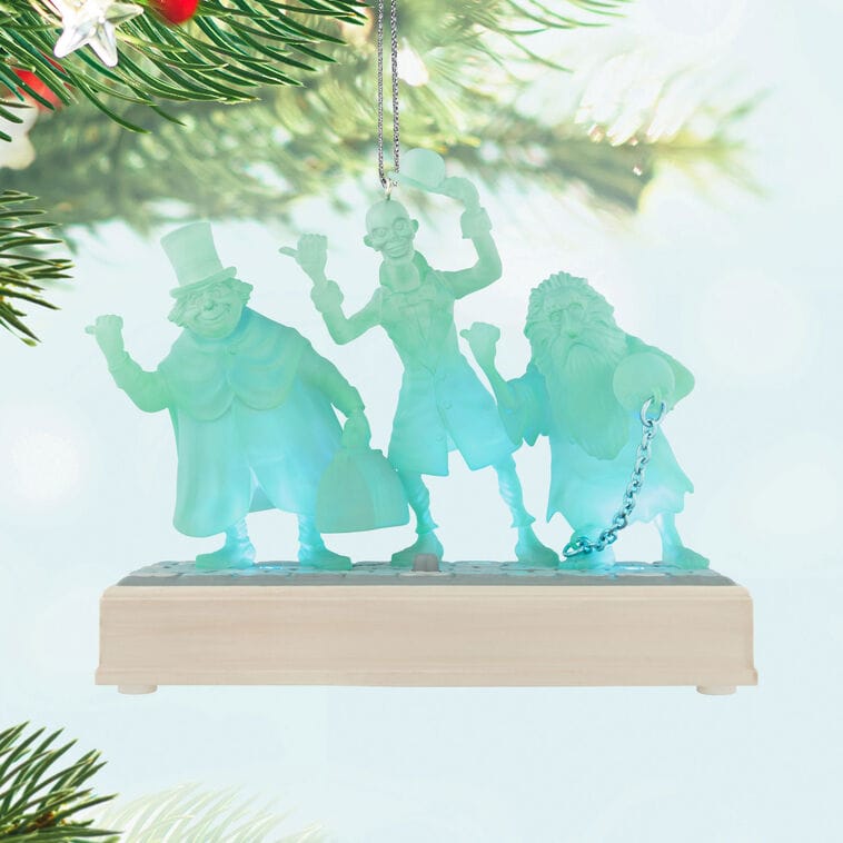 Translucent blue Haunted Mansion ghost ornaments, from Disneyland or Disney World, dangle on a Christmas tree branch.