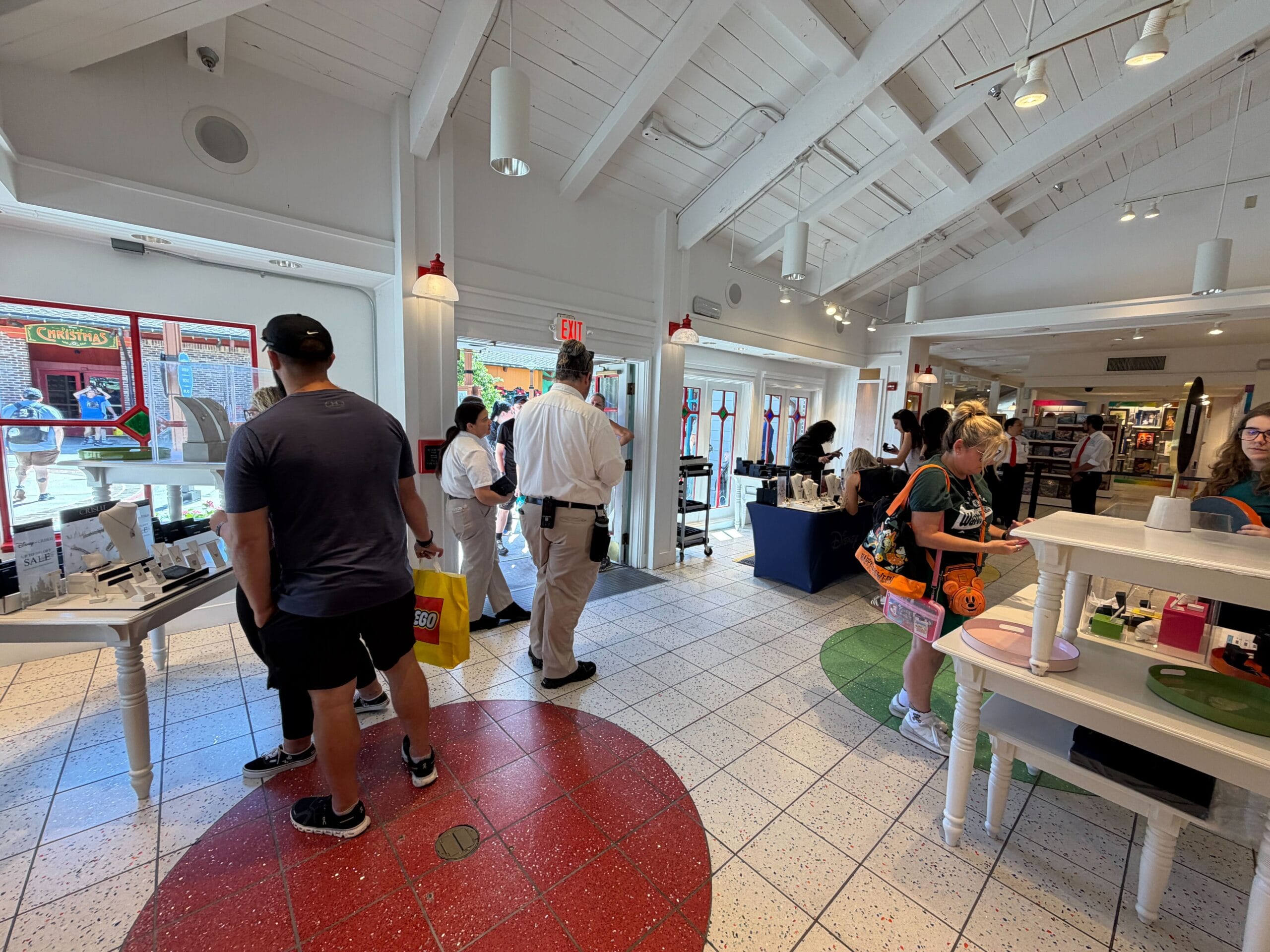 Guests shop and explore displays in a bright, open CRISLU store at Disney, with white walls and vibrant, mosaic-like floors.