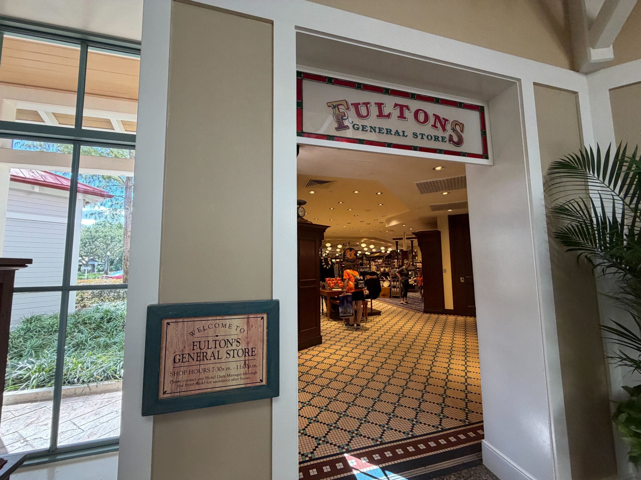 Fulton's General Store entrance at Disney Park, sign outside and warm interior filled with themed merchandise visible inside.