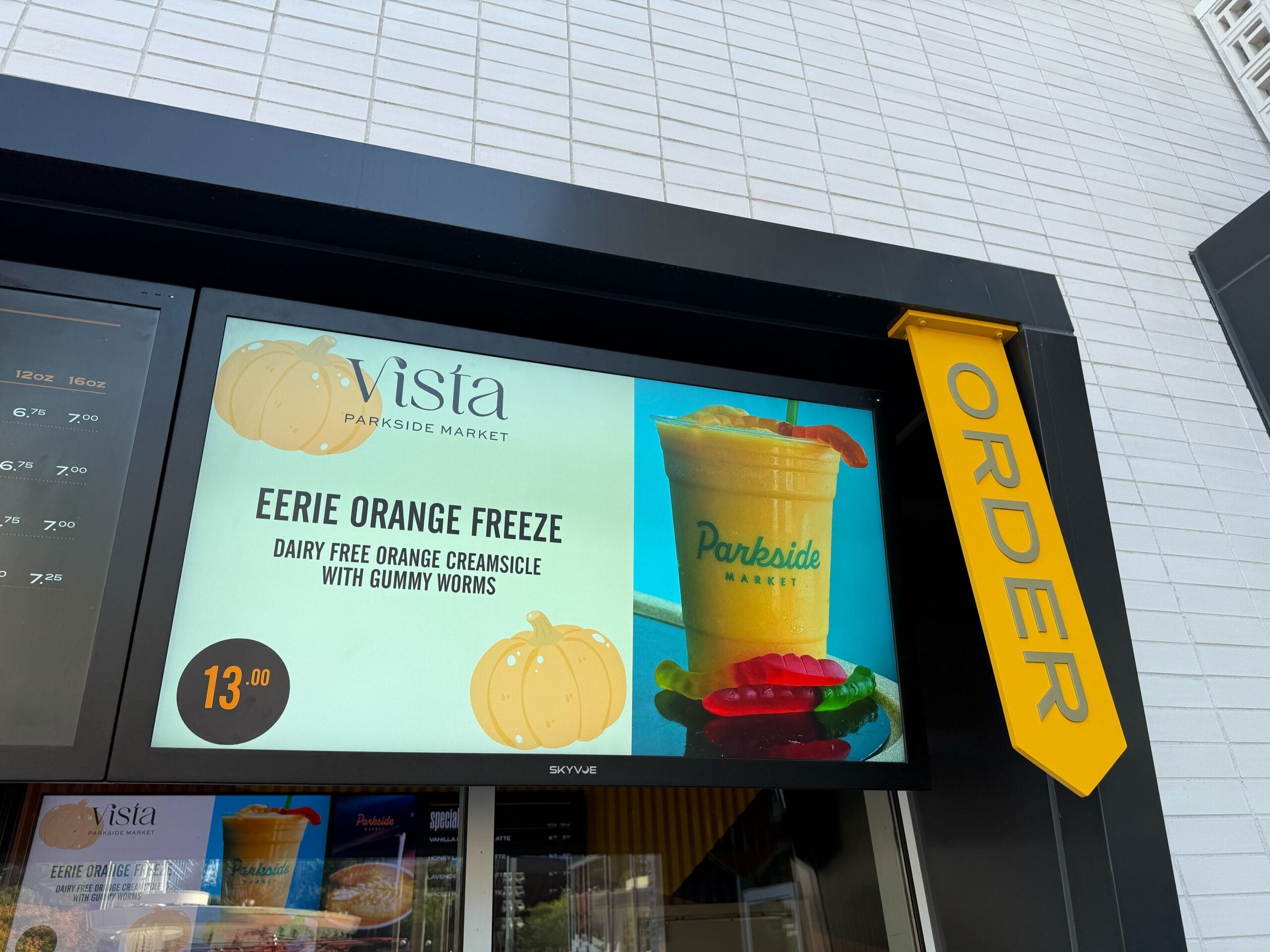 Parkside Market drive-thru menu showcases the "Eerie Orange Freeze" with gummy worms for $13, a treat found at Disney Parks.