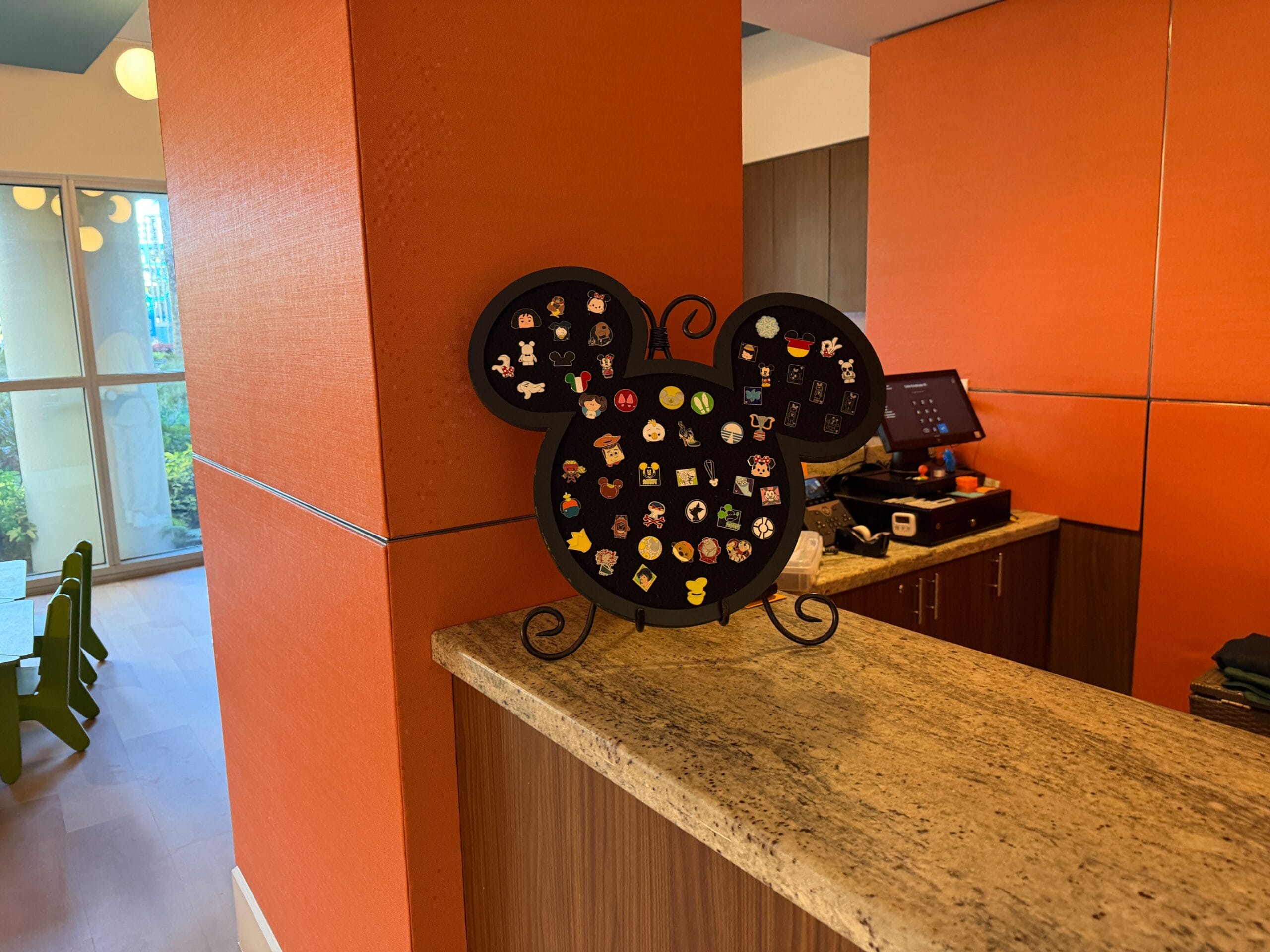 A Mickey-shaped Disney pin board sits on a granite counter at Bay Lake Tower, with a modern vibe reminiscent of Disney resorts.