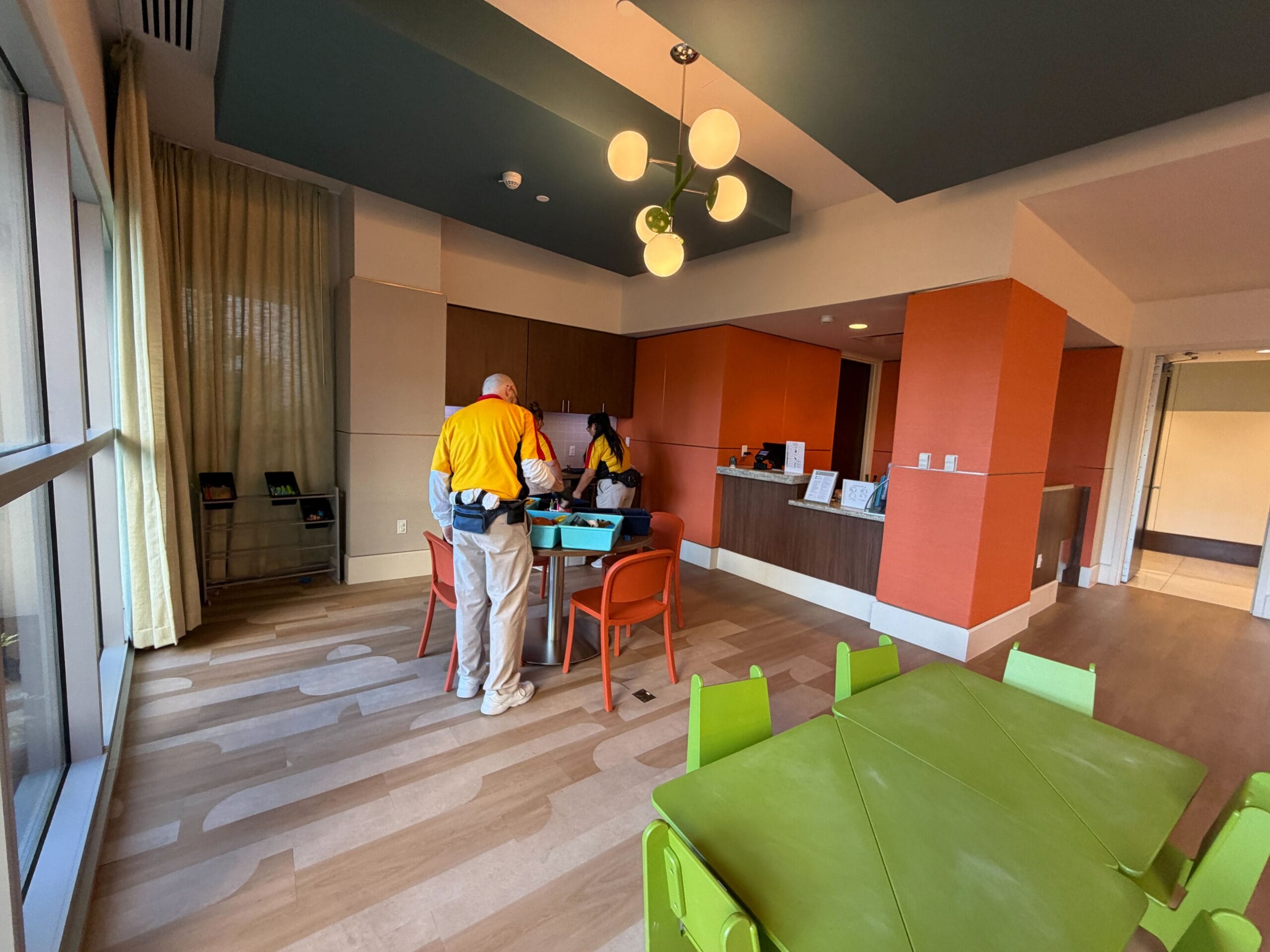 Two adults and a child stand by green kids’ furniture in a bright, modern Bay Lake Tower room at Walt Disney World Resort.