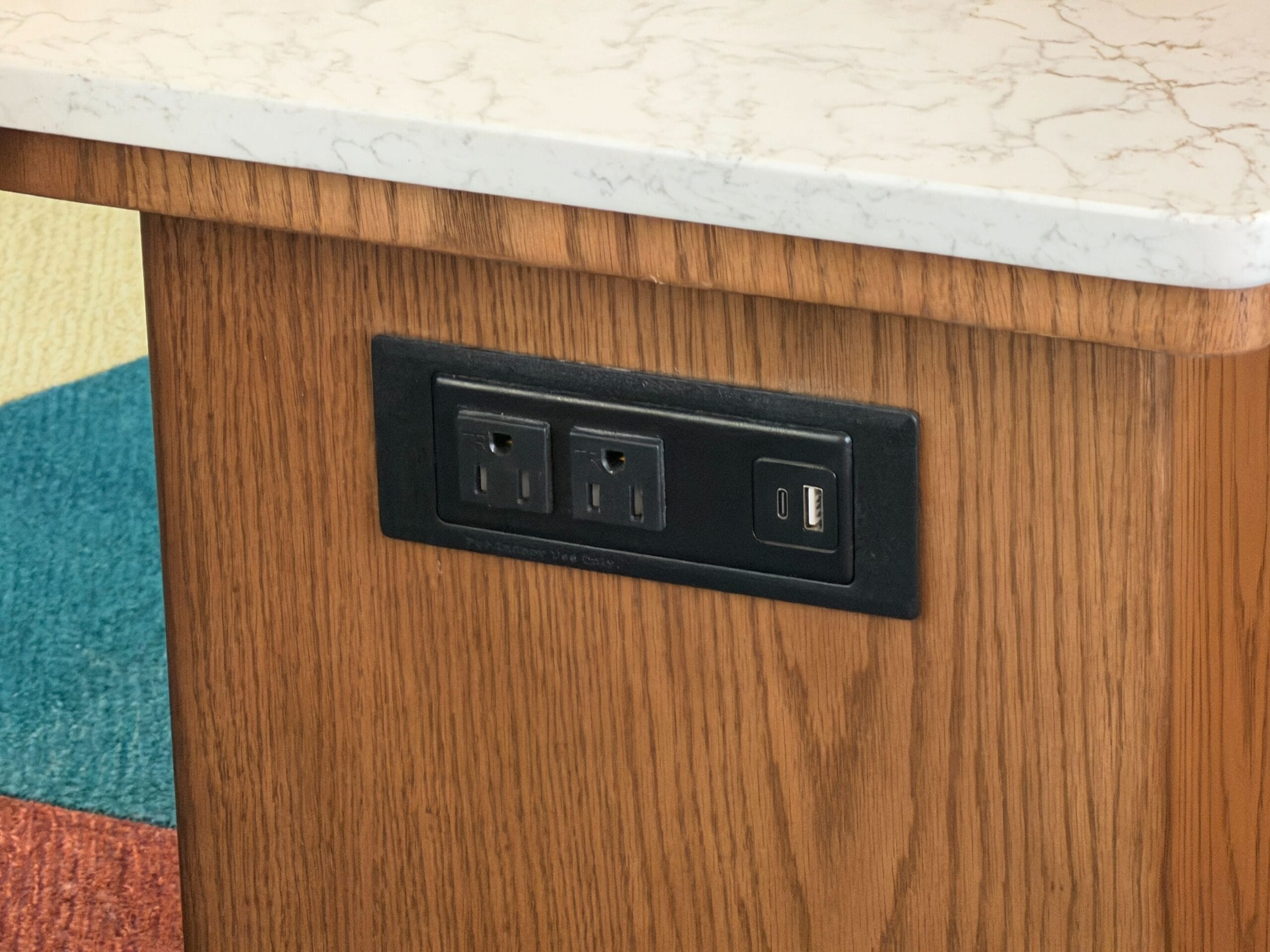 Two outlets and a USB port set in wood beneath marble—modern touches perfect for rooms at Disney’s Contemporary Resort or Bay Lake Tower.