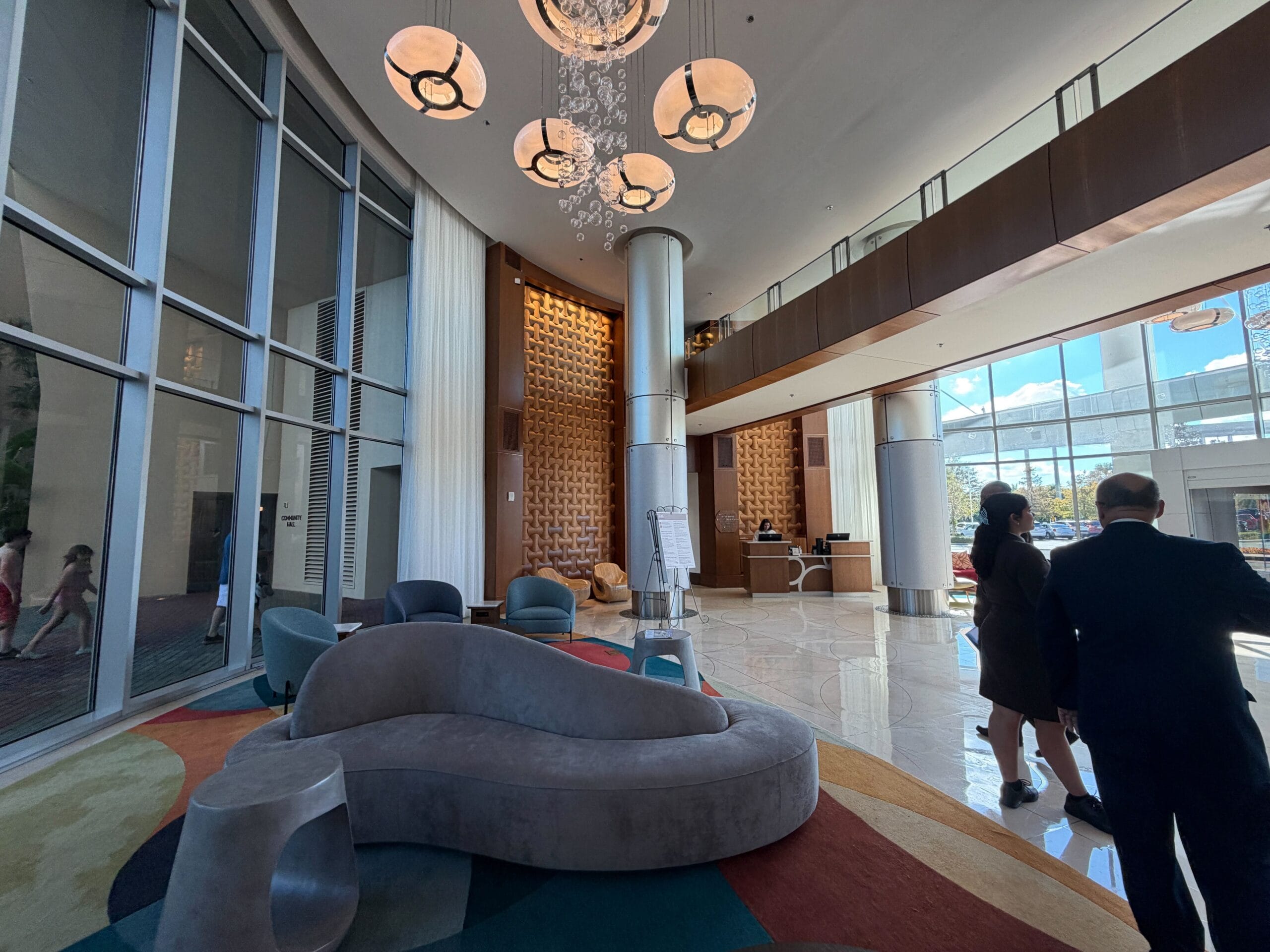 Chic lobby at Bay Lake Tower, Disney resort, with elegant decor, bright chandeliers, and guests near entrance—no castle in view.