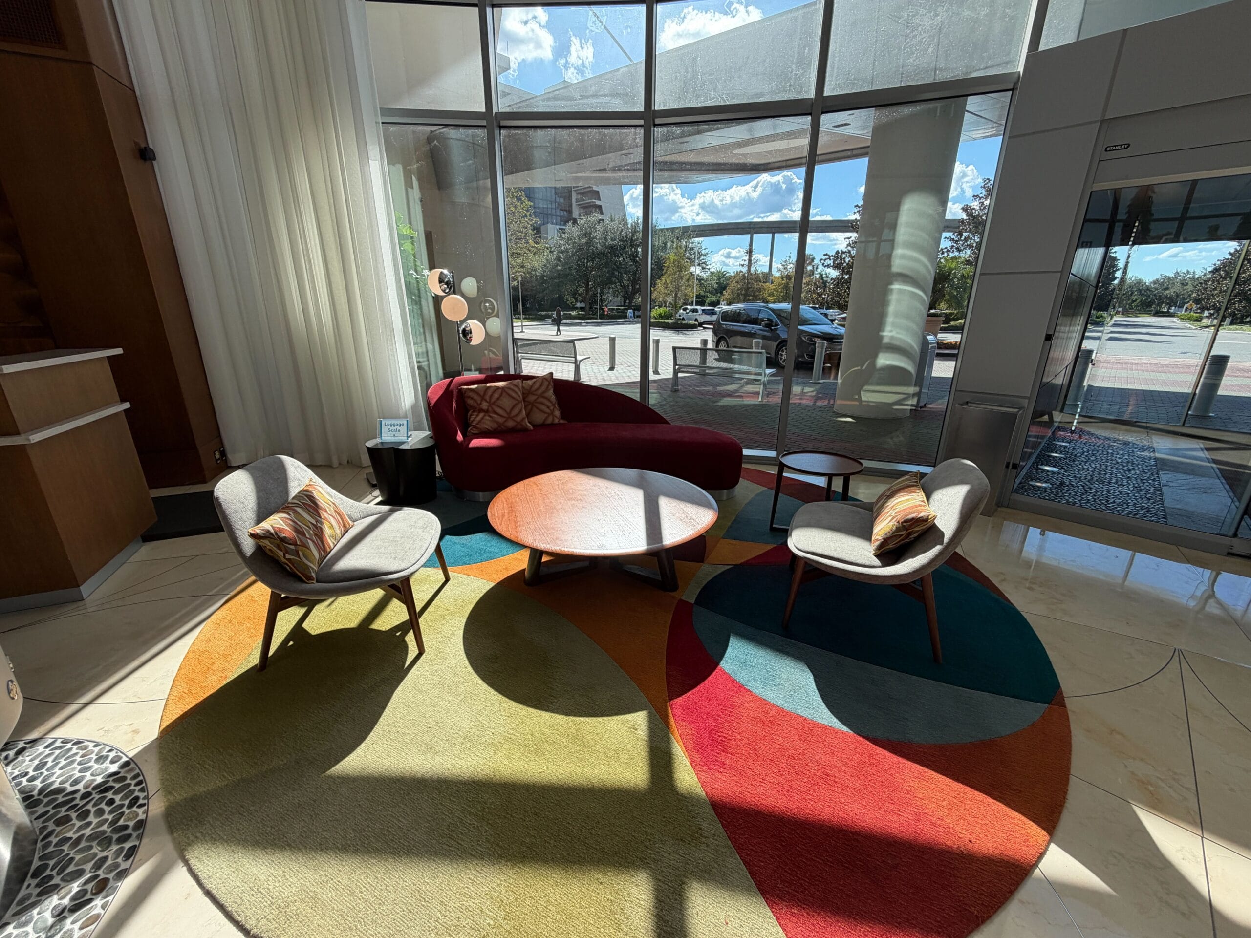 A stylish Bay Lake Tower lobby at Walt Disney World, featuring a vibrant rug, chic seating, and sunny windows—not a castle view.