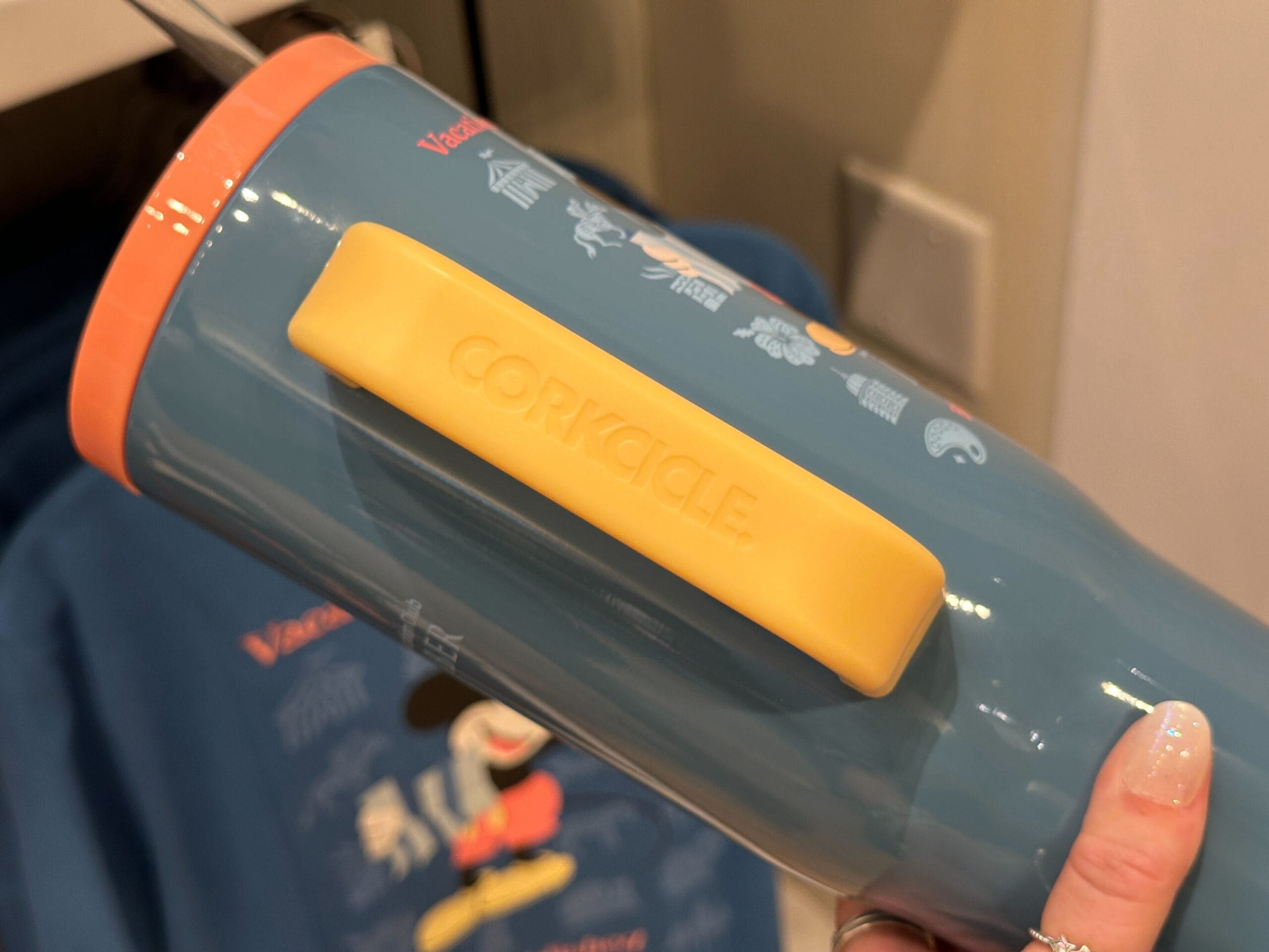 A hand holds a blue Corkcicle tumbler from the new DVC Member Merch collection, in front of a blue shirt.