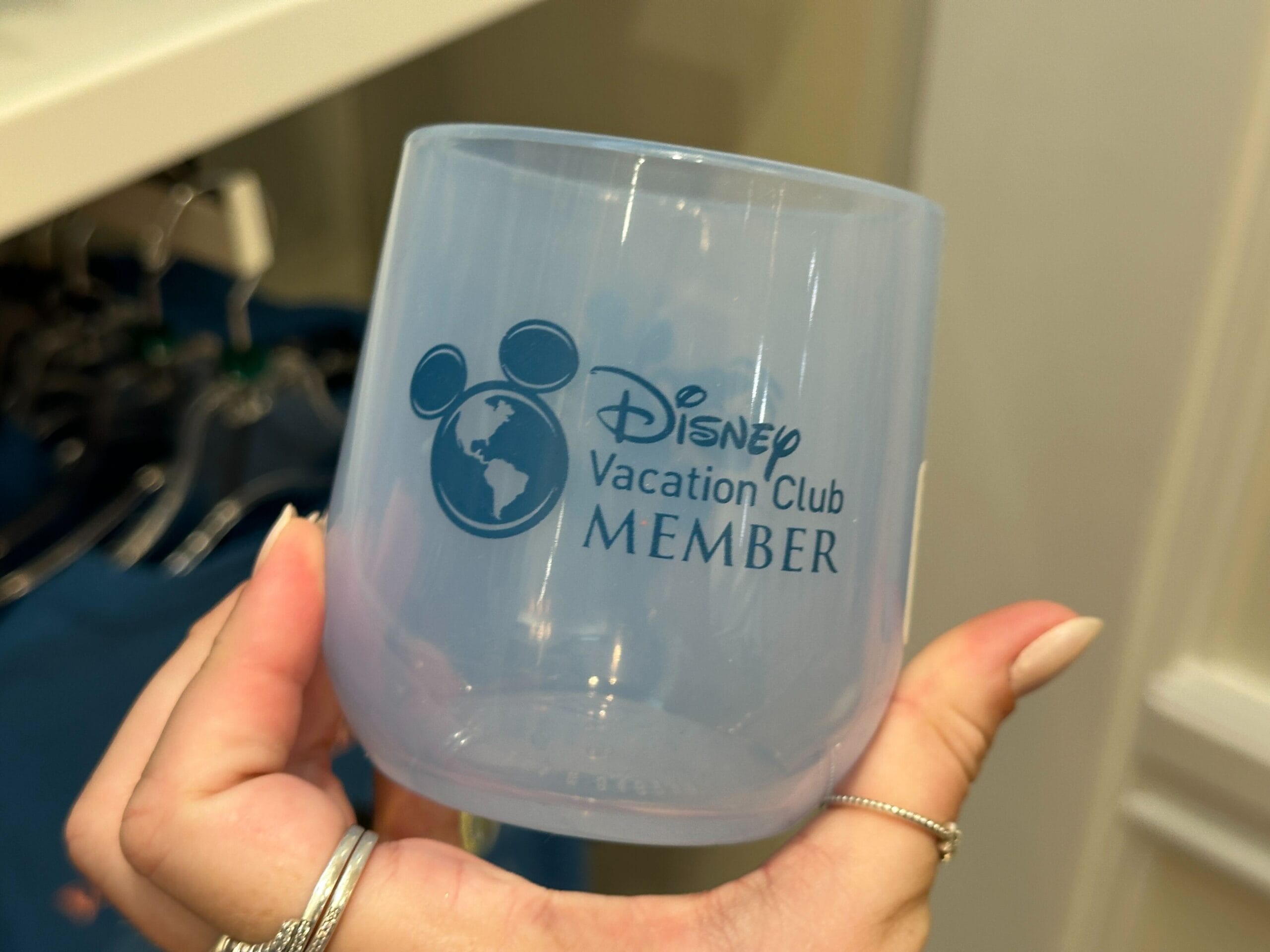 A hand holds a clear cup with "DVC Member" and Mickey Mouse logo, part of the Grand Floridian Merch Collection.