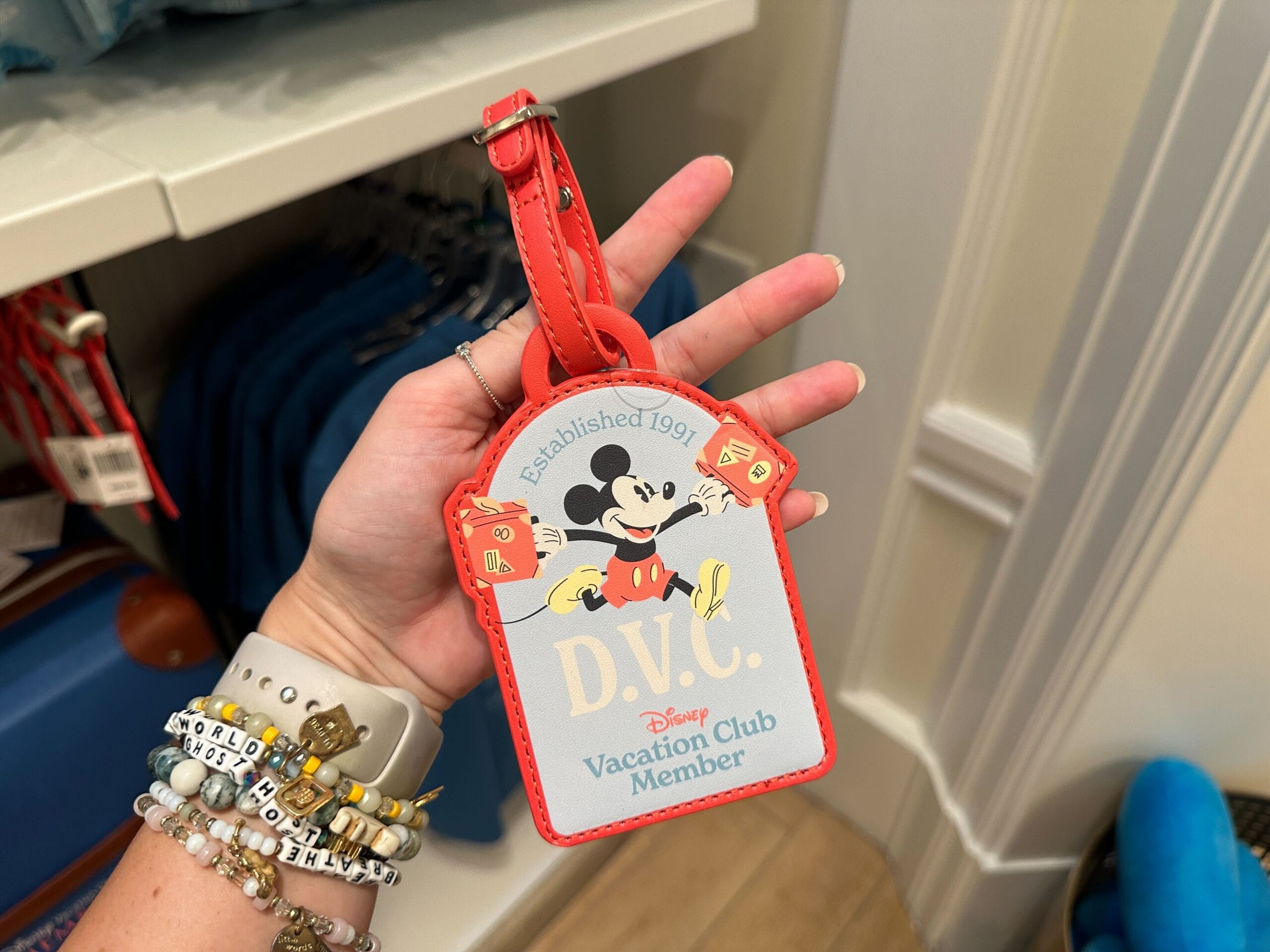 Hand holding a DVC Member Merch luggage tag featuring Mickey Mouse and "Established 1991" at Grand Floridian.