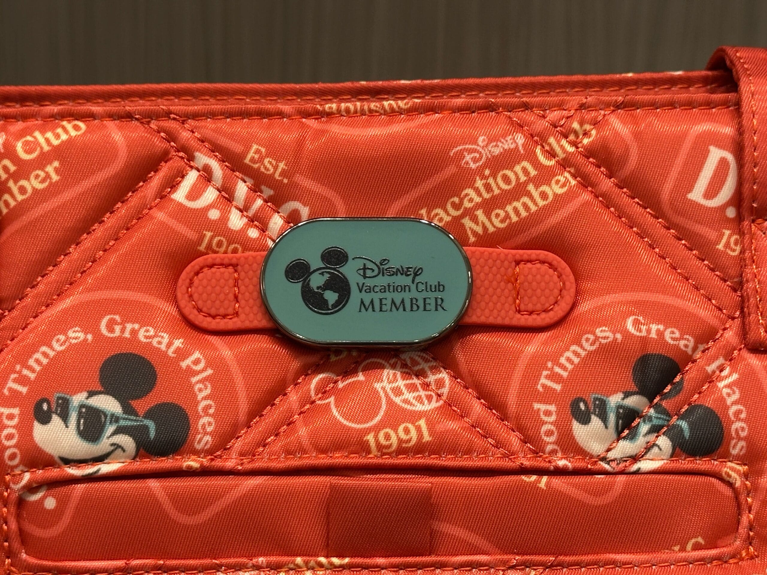 Close-up of a red DVC Member Merch bag with Mickey Mouse faces and "Good Times, Great Places" text pattern.