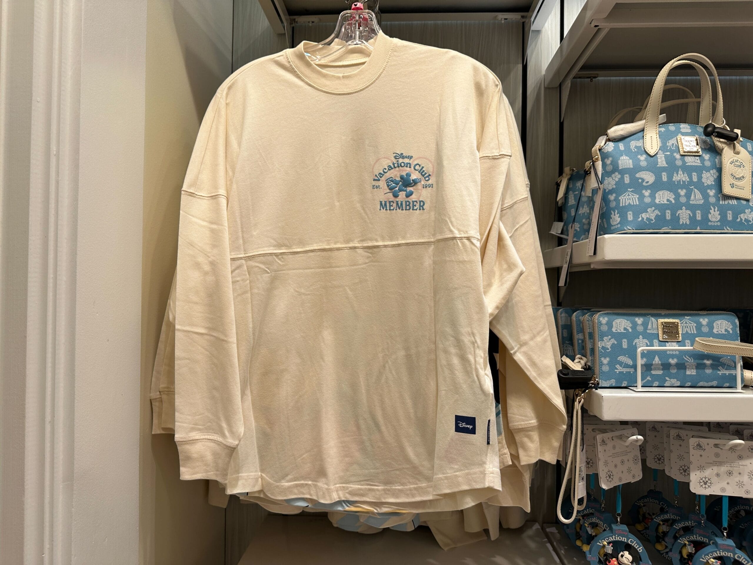 Front of cream Disney Vacation Club Member-exclusive Spirit Jersey with a blue Mickey Mouse on the chest and the text "Disney Vacation Club Member Est. 1991."