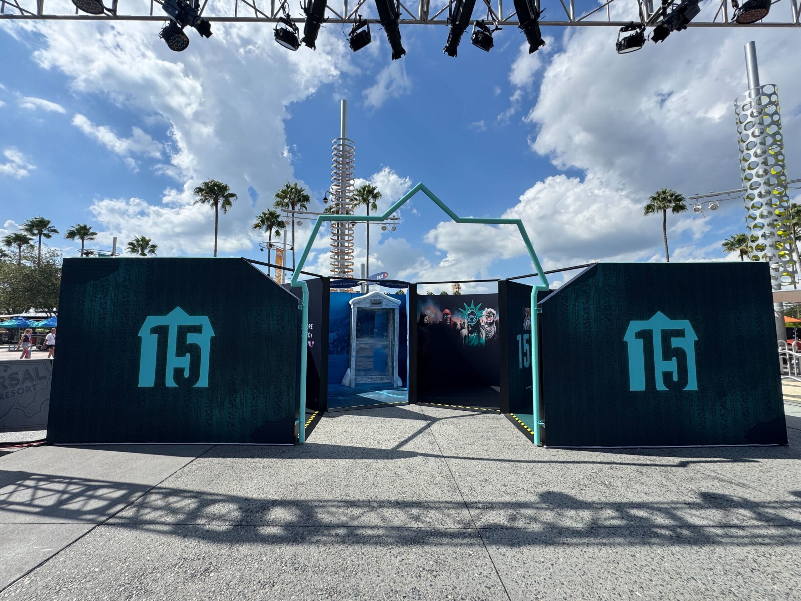 Outdoor event setup at Universal CityWalk with "15" signs, a glass booth, and palm trees for the 15th Anniversary.