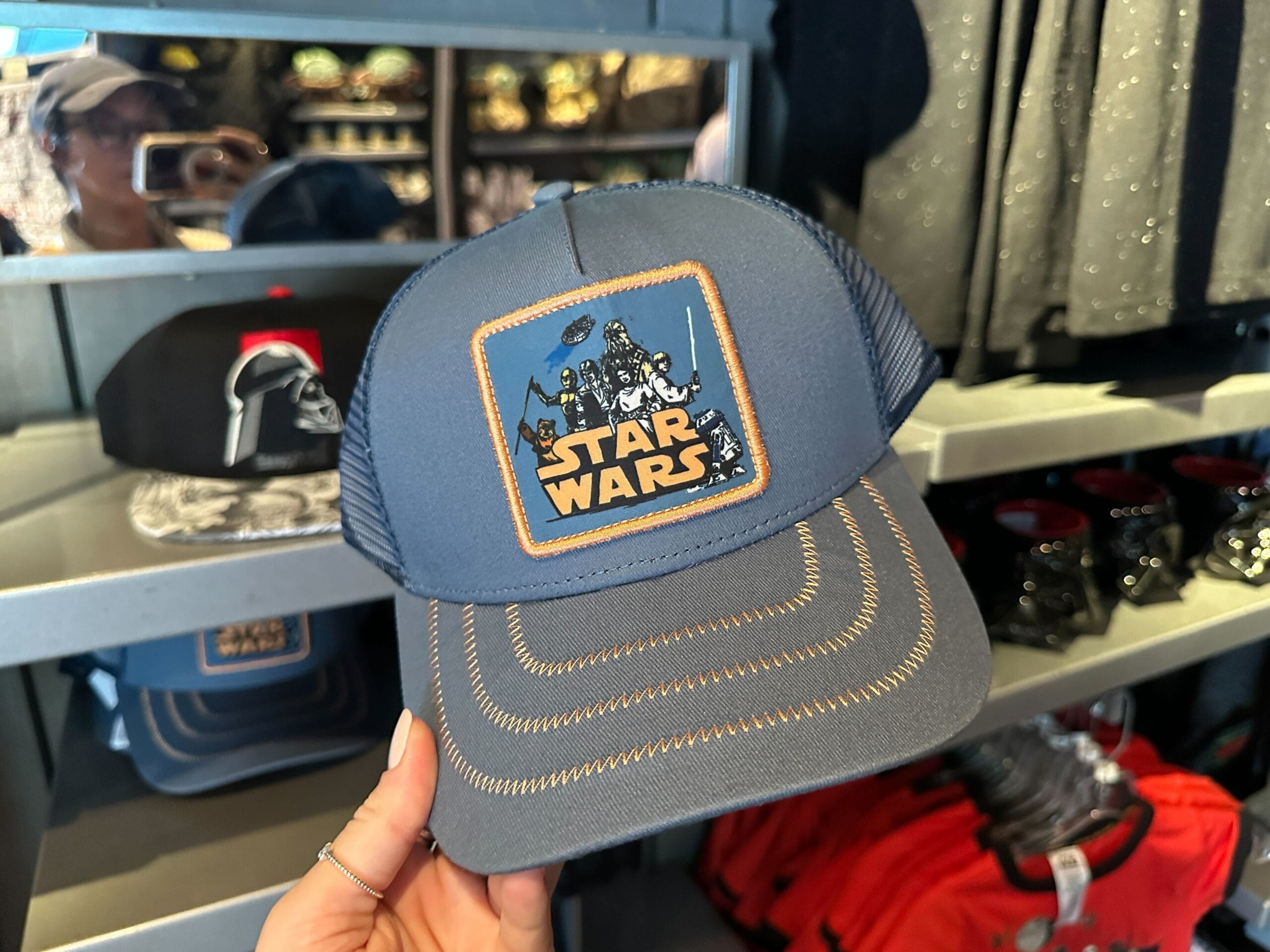A blue Star Wars trucker hat with a character patch of the Rebel heroes and an orange Star Wars logo.
