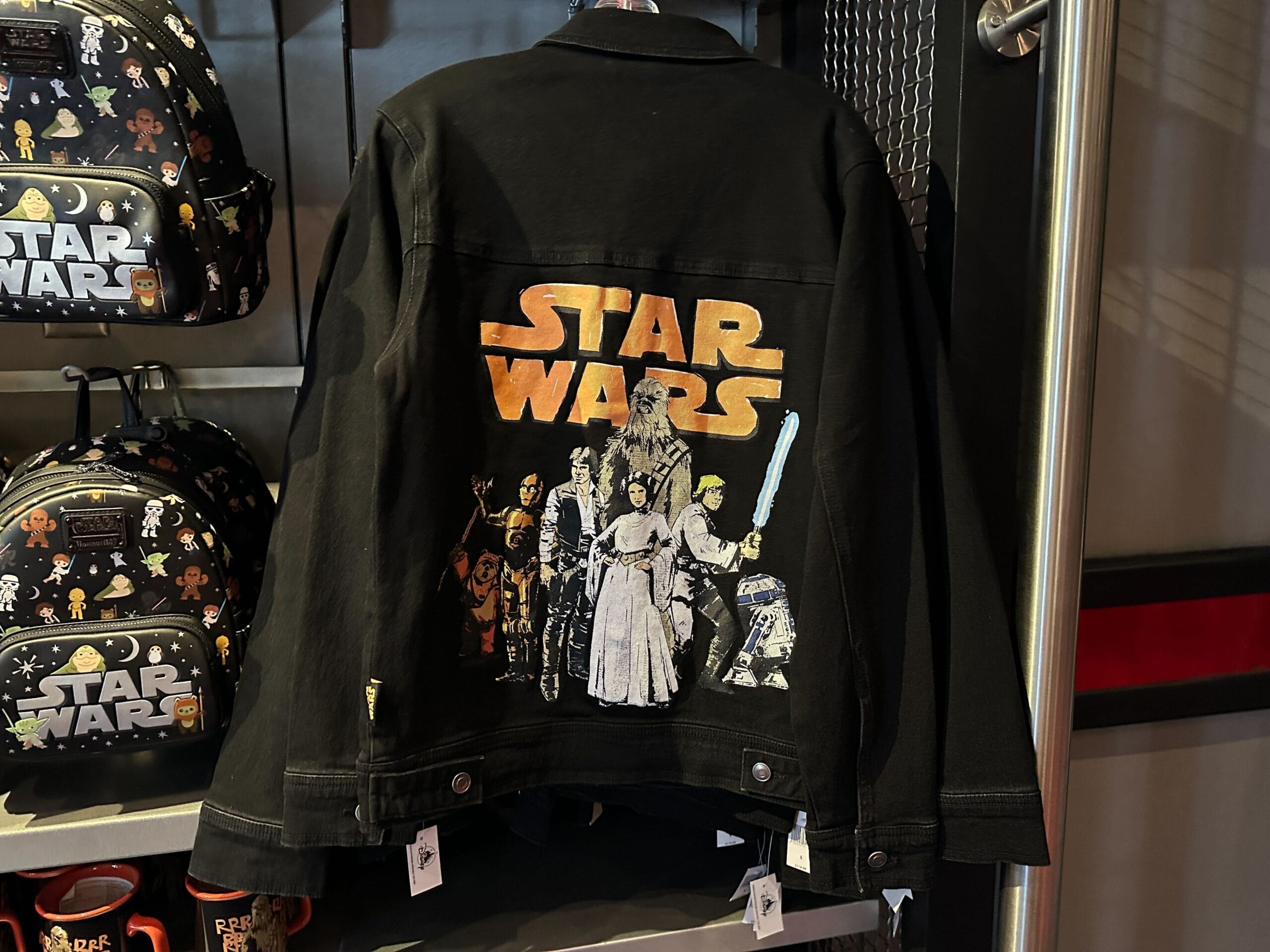 A black jacket with a colorful Star Wars graphic featuring main characters displayed on the back below an orange Star Wars logo.