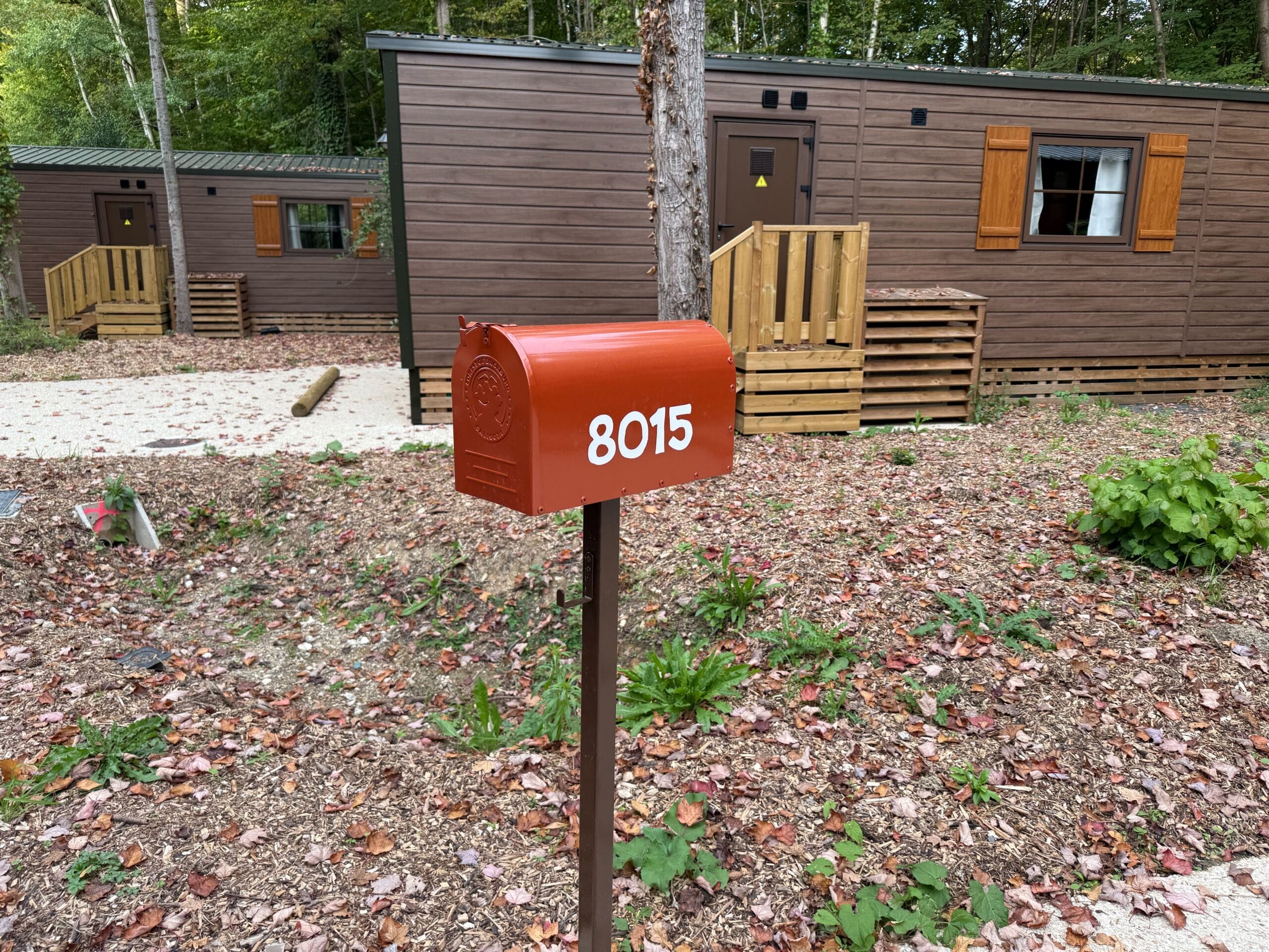 Red mailbox “8015” stands outside a standard cabin at Davy Crockett Ranch in Disneyland Paris.