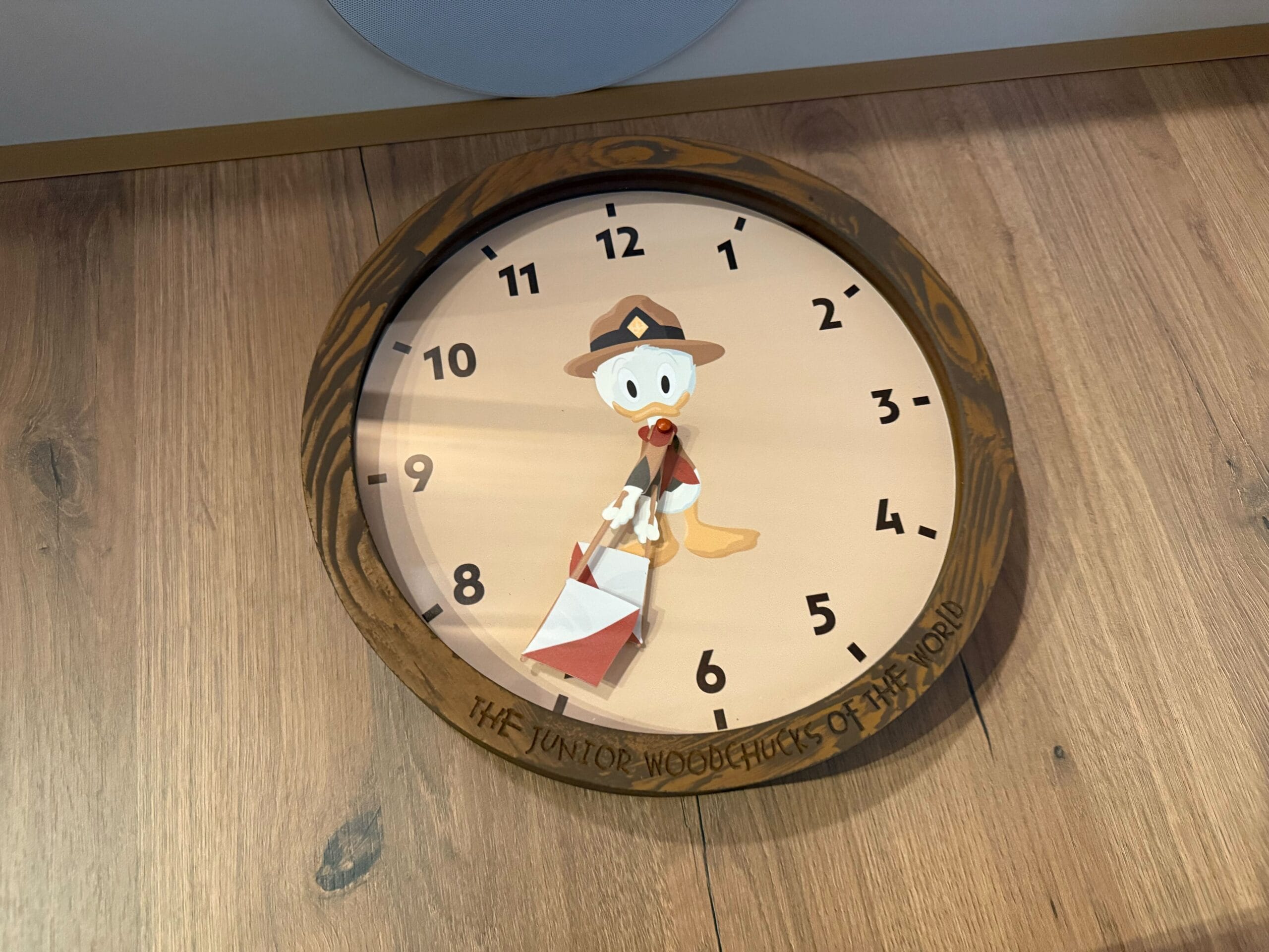 A wall clock featuring Huey in a scout uniform holding semaphore flags, hanging in a cabin at Davy Crockett Ranch at Disneyland Paris.
