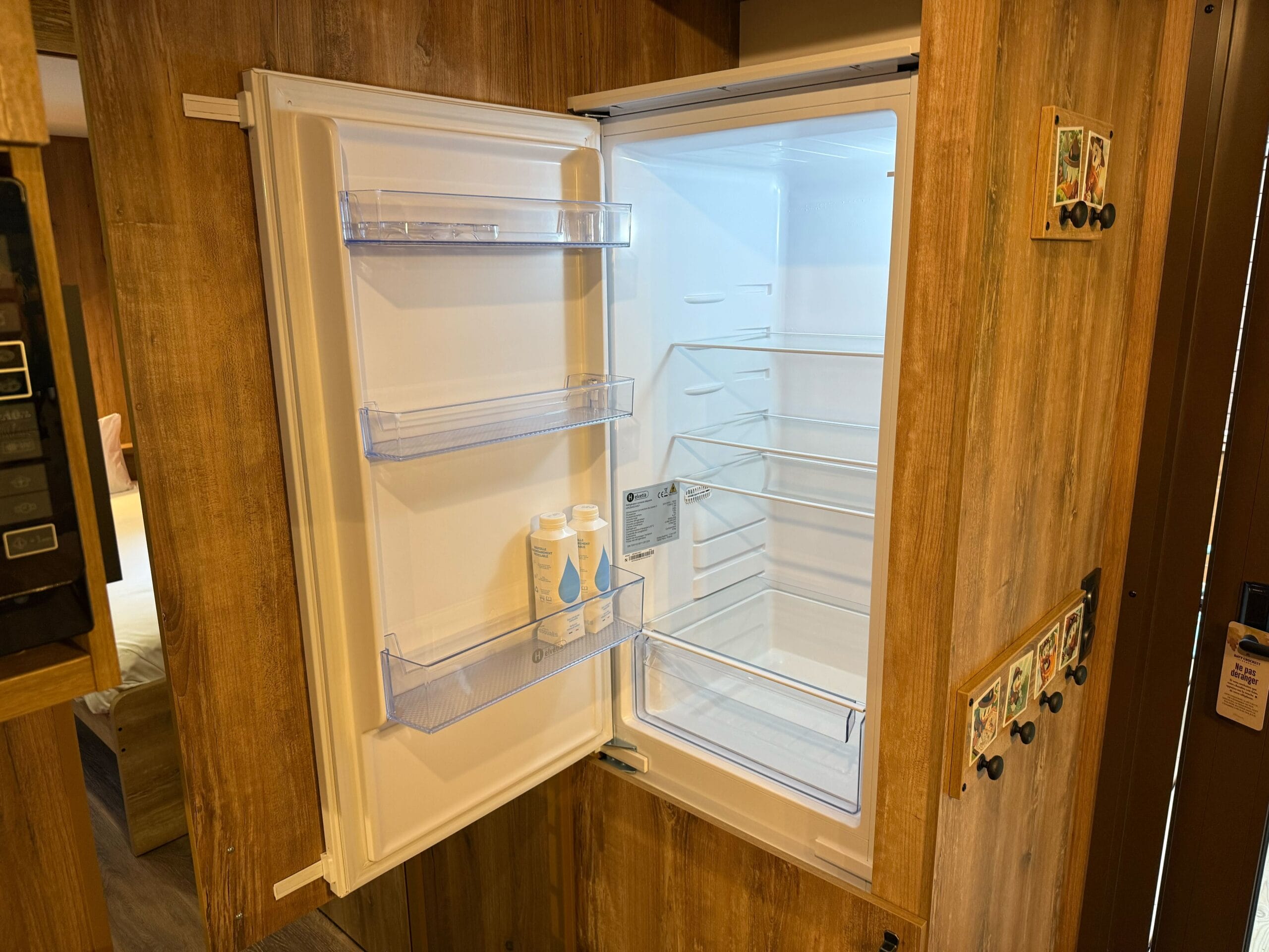 An open fridge inside a cozy, wood-paneled Davy Crockett Ranch Cabin Room at Disneyland Paris Resort.