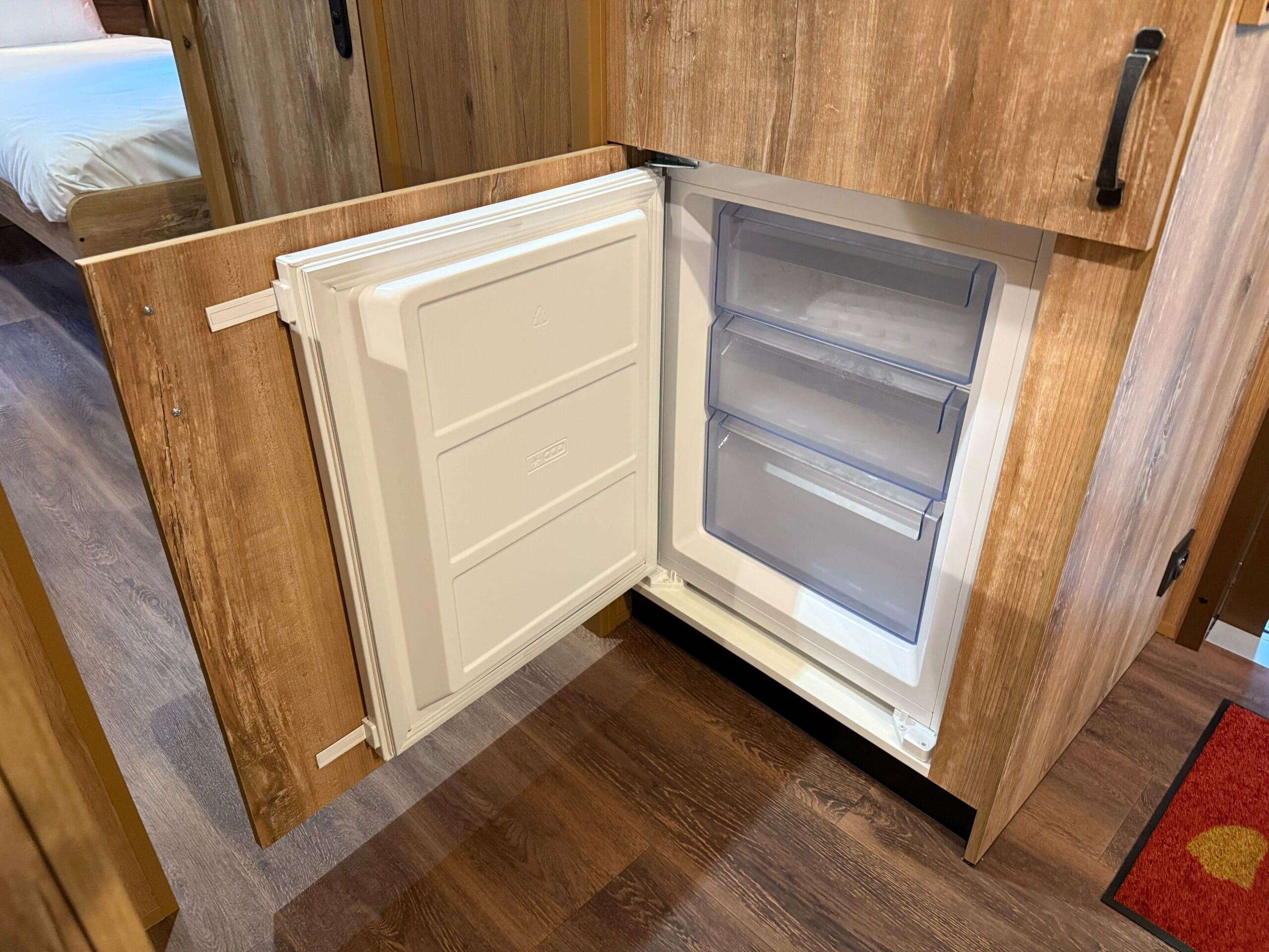 A compact built-in freezer with its door open in a cozy Davy Crockett Ranch cabin at Disneyland Paris.