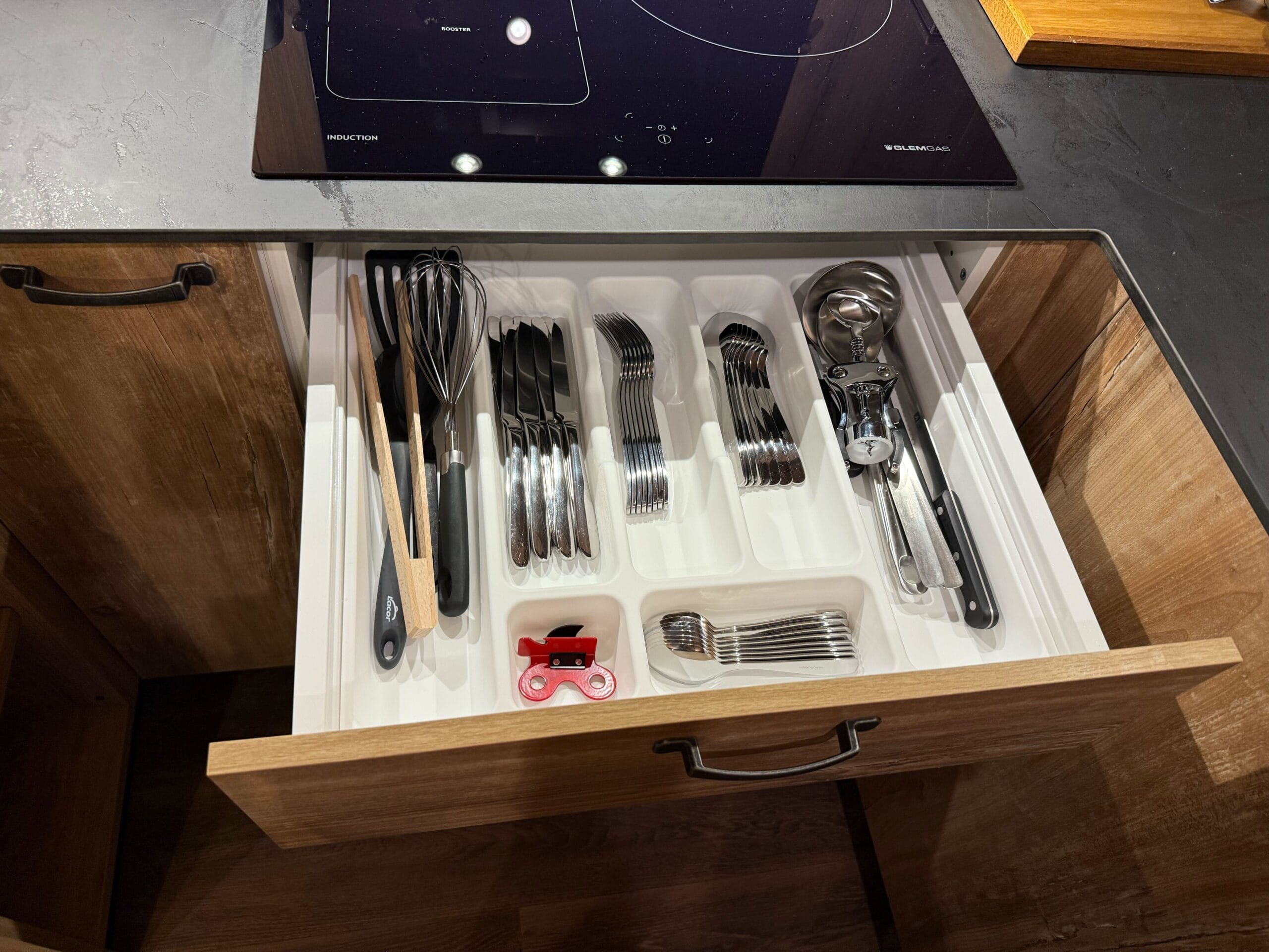 Open kitchen drawer showing neat cutlery and a red bottle opener, in a cabin at Davy Crockett Ranch at Disneyland Paris.