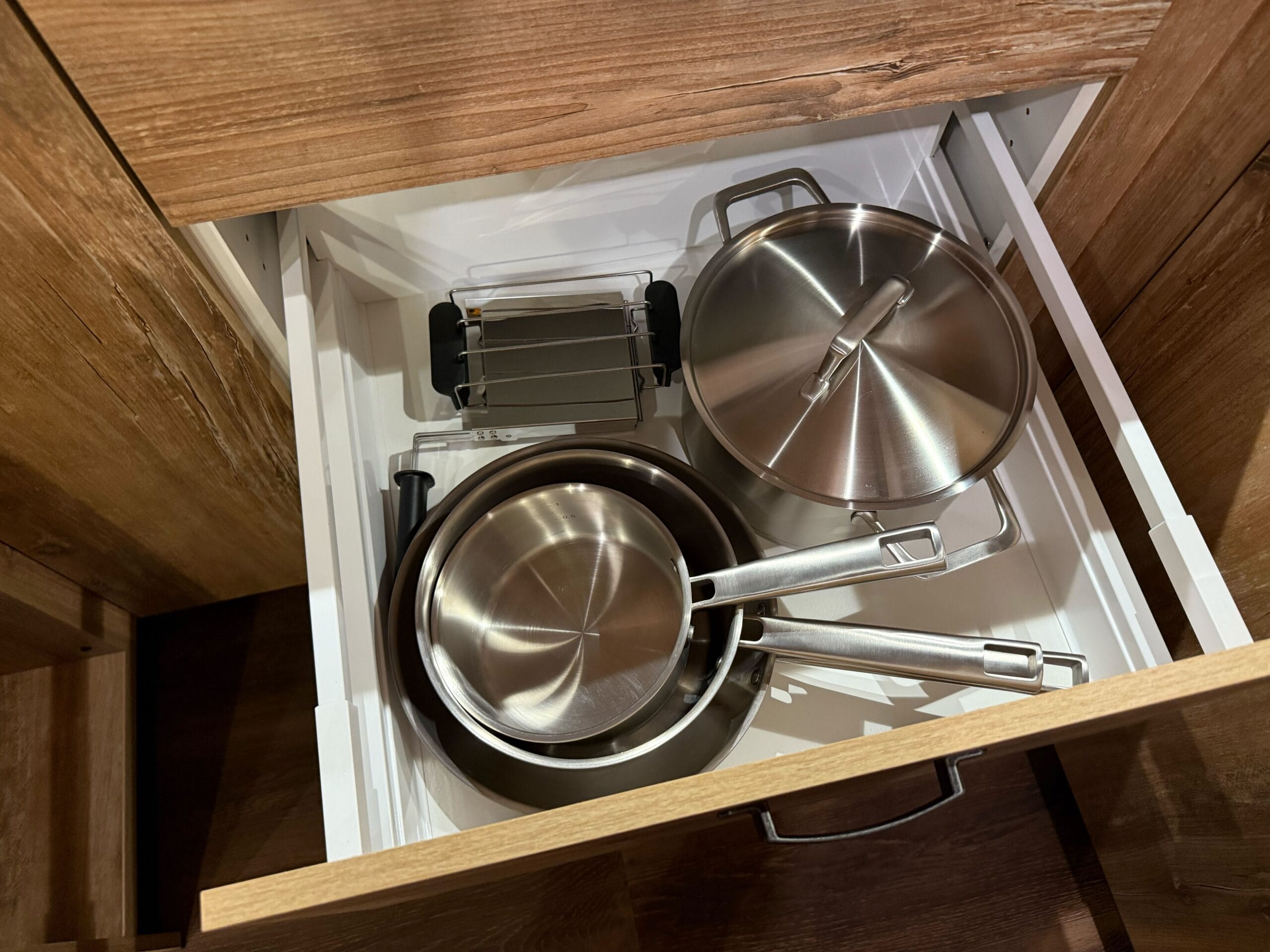 Open kitchen drawer with neatly arranged pots and pans inside, in a cabin at Davy Crockett Ranch at Disneyland Paris.