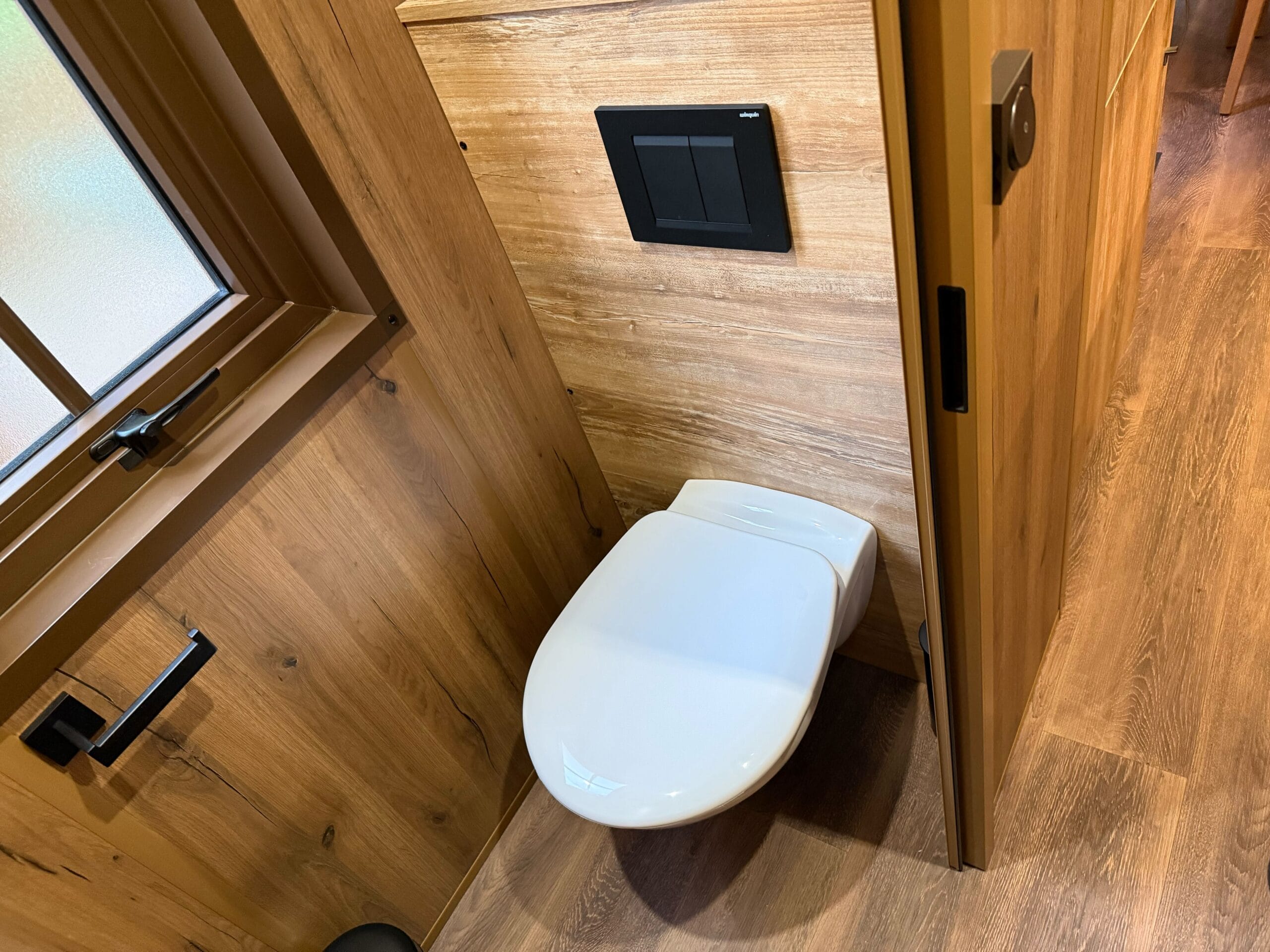 A sleek white wall-mounted toilet in a Standard Cabin Room at Davy Crockett Ranch, Disneyland Paris.