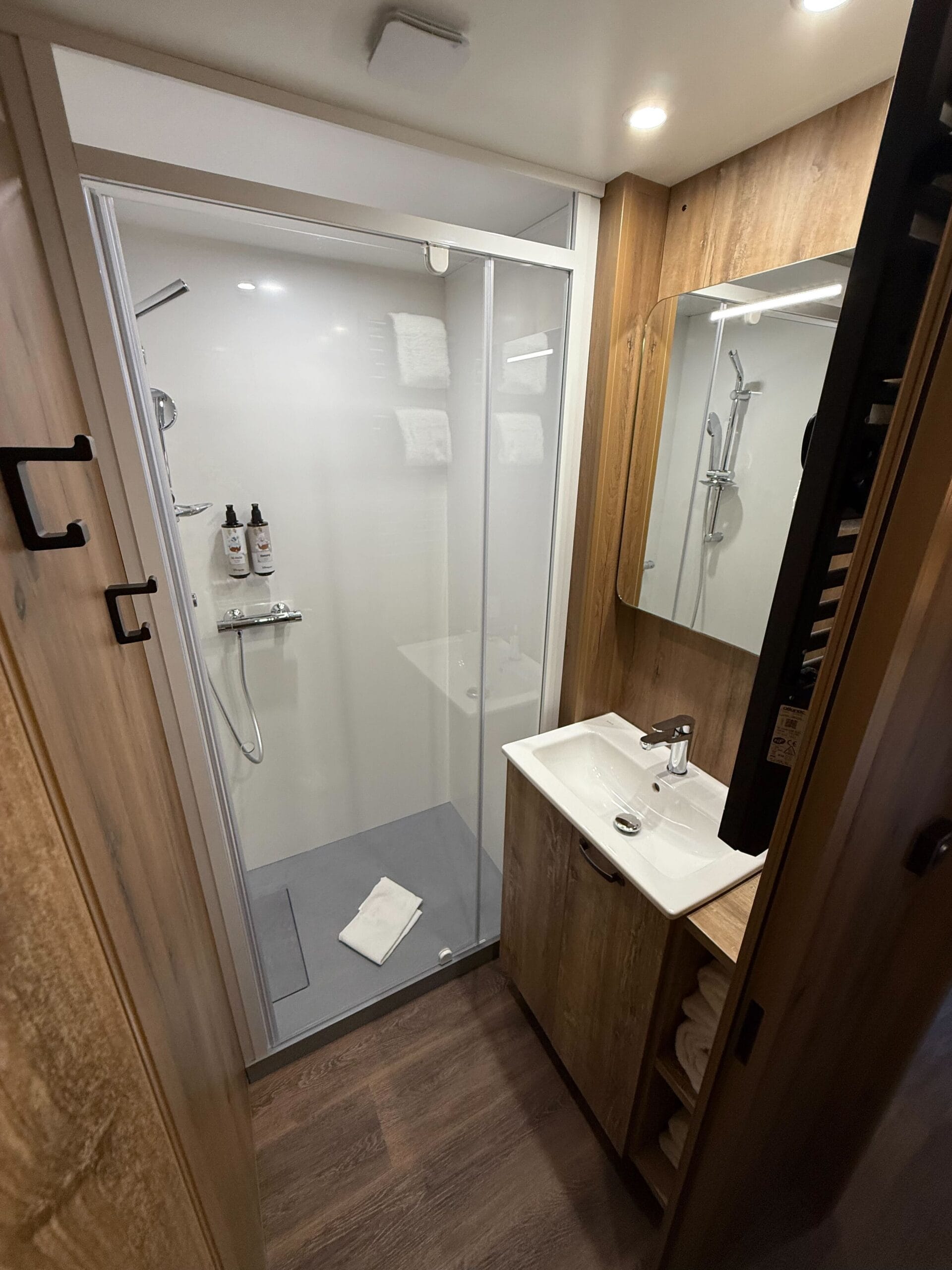 Modern bathroom at Disney's Davy Crockett Ranch cabin, with glass shower, wood accents, and towel on the floor.