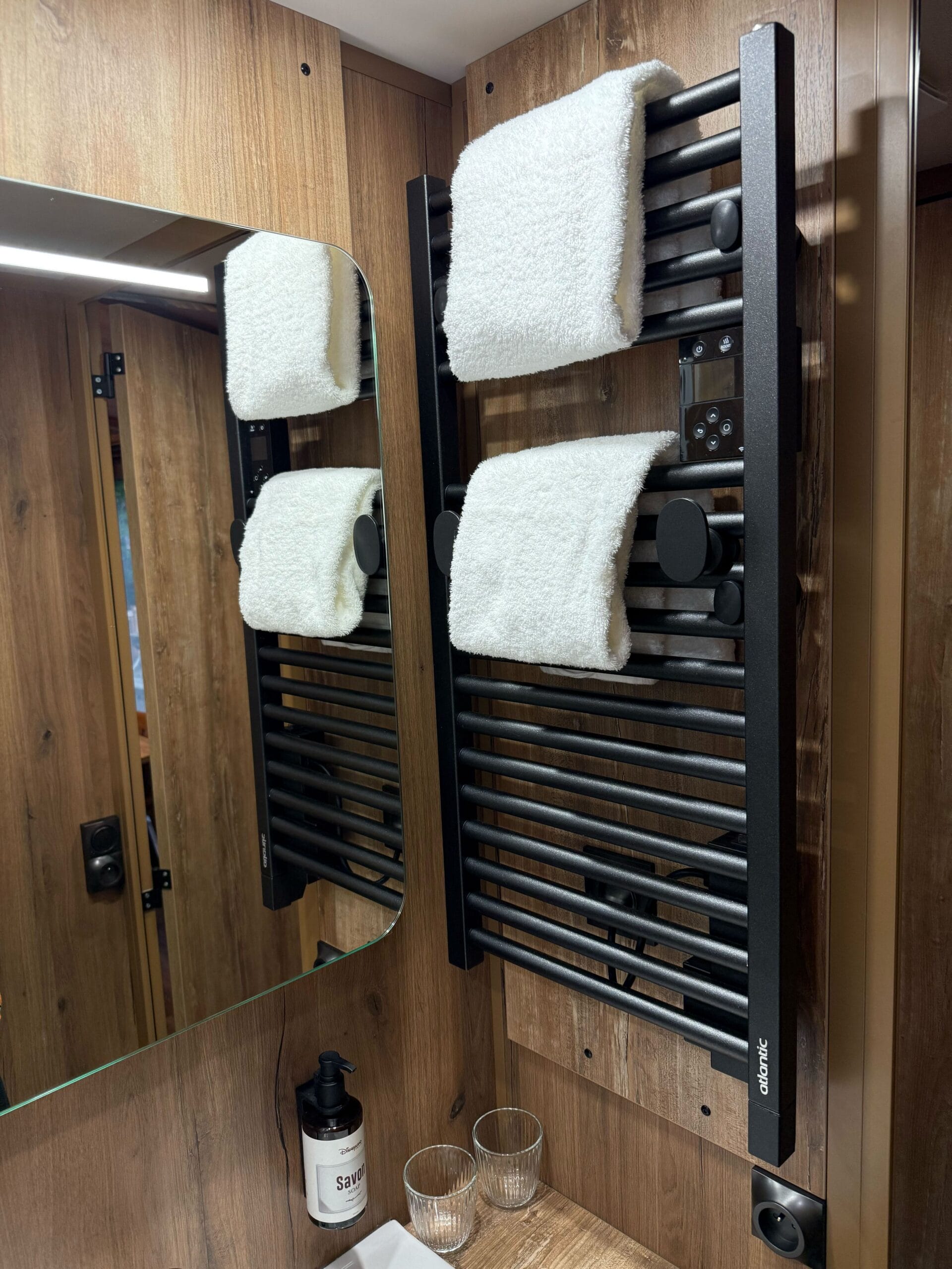 A black heated towel rail with two white towels in a Standard Cabin Room at Disney’s Davy Crockett Ranch, near Disneyland Paris.
