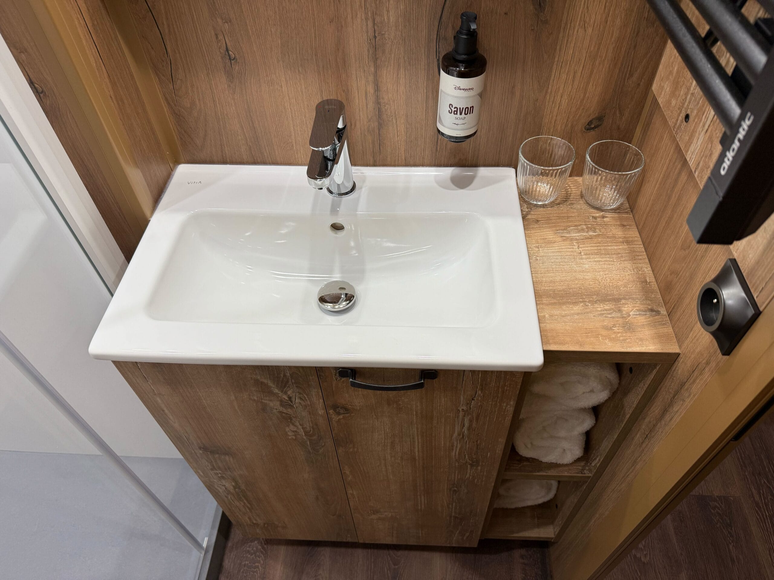 White sink with chrome faucet set in a wooden vanity, seen in the Standard Cabin Room at Davy Crockett Ranch, Disneyland Paris.