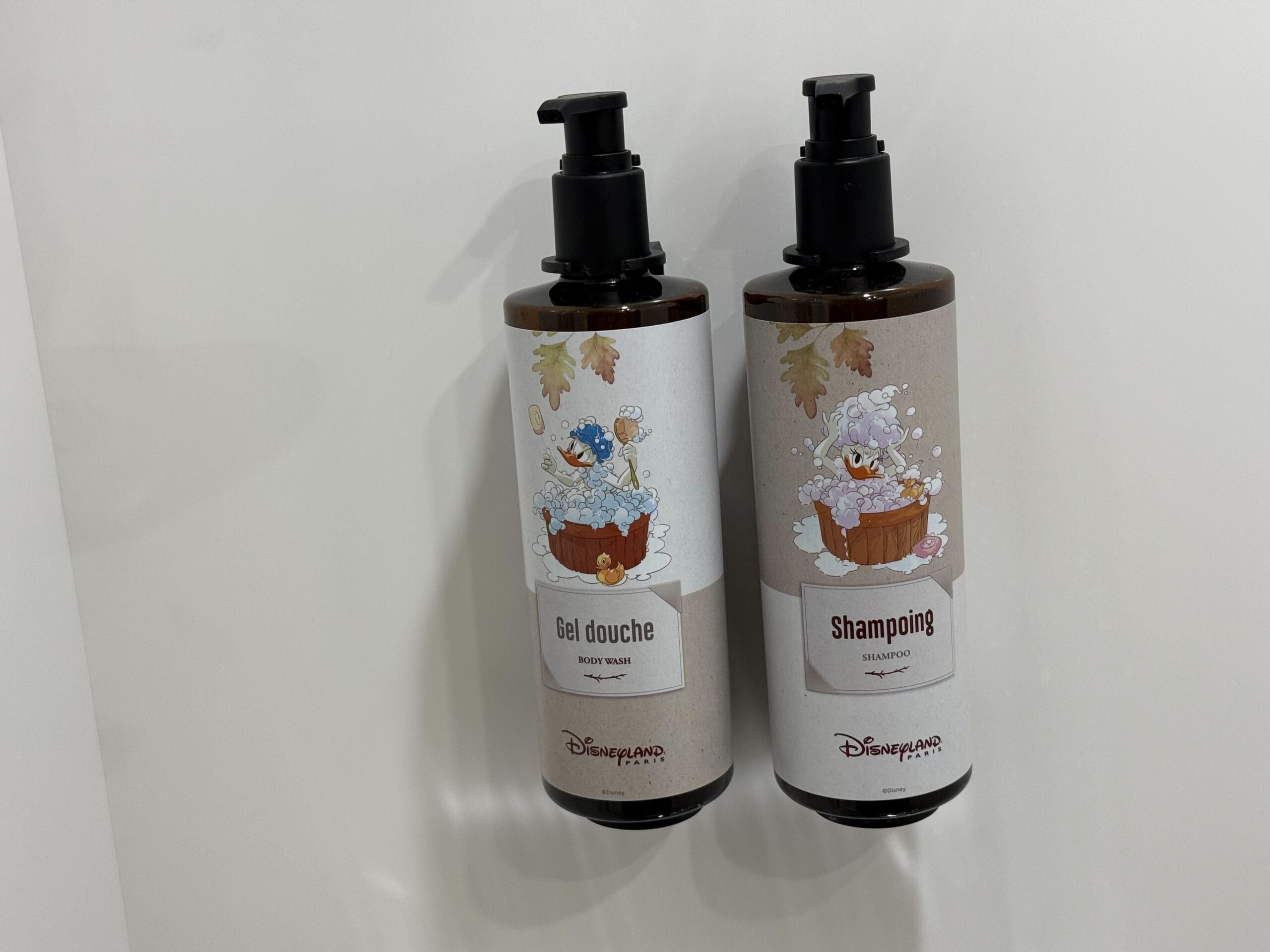 Two Disney bottles labeled "Gel douche" and "Shampoing" with artwork of Donald and Daisy in wash tubs.