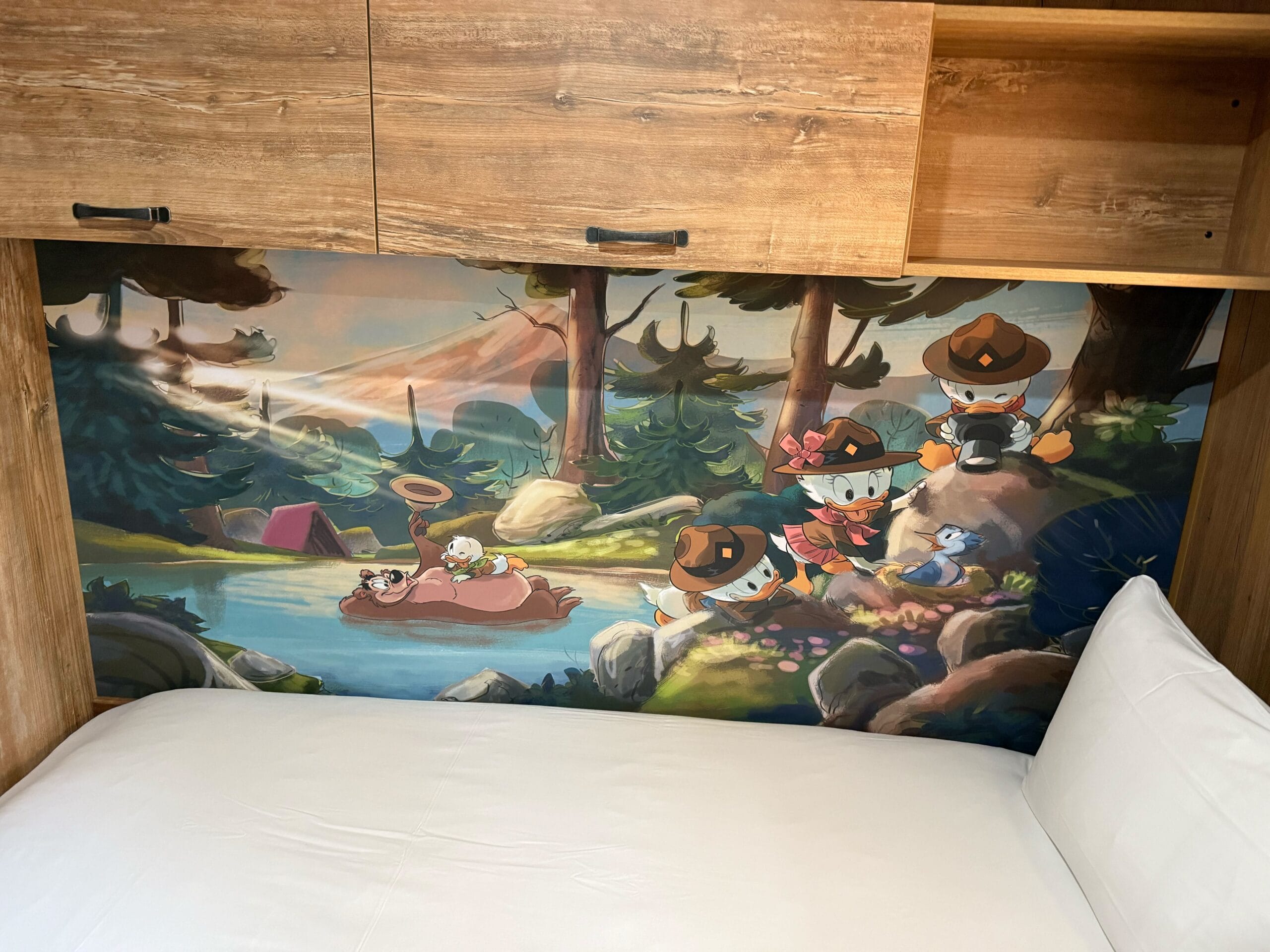 A mural above a bed shows Huey, Dewey, Louie, and Webby Vanderquack enjoying scouting activities in a forest scene.