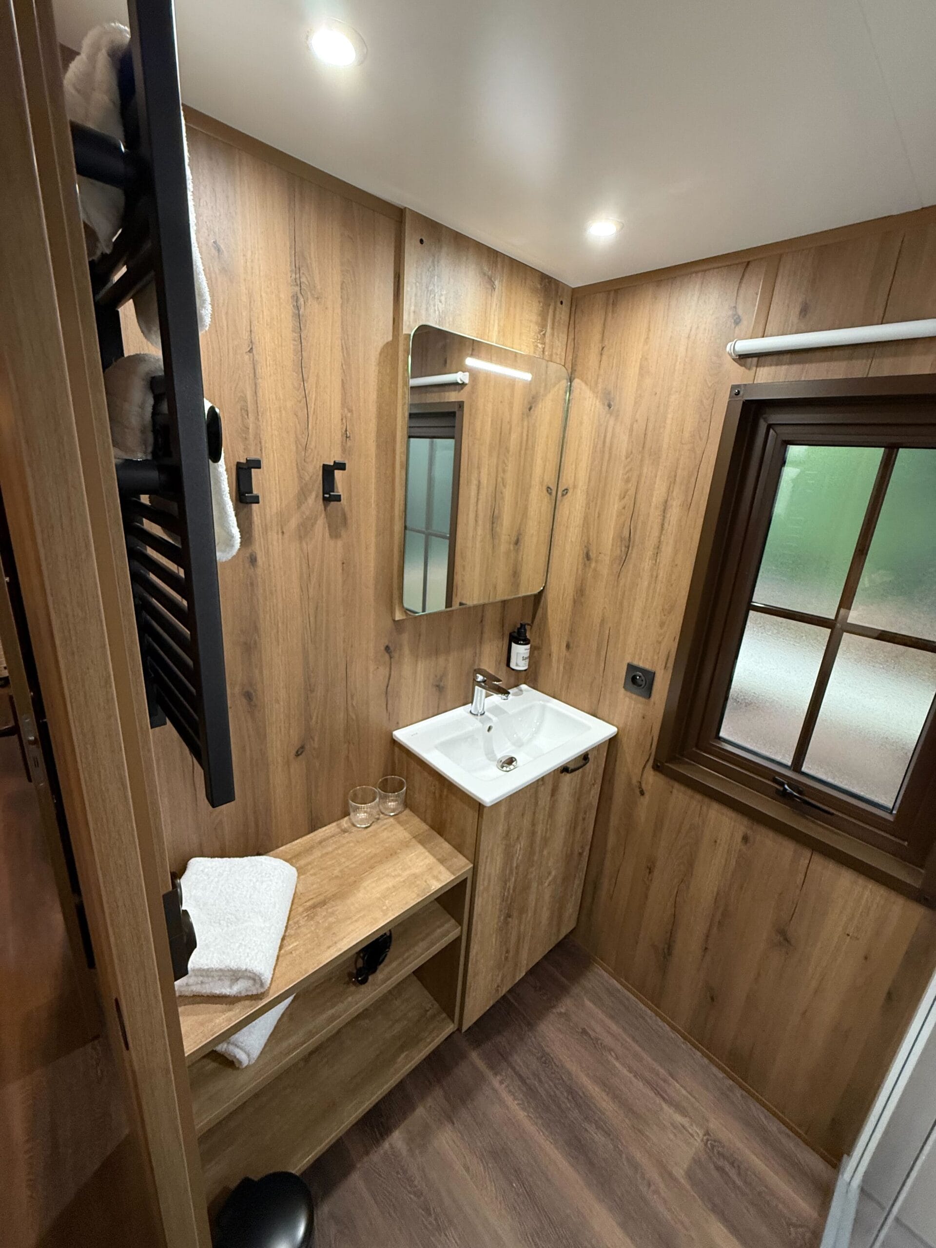 A cozy, modern bathroom at Davy Crockett Ranch in Disneyland Paris, featuring wood-paneled walls and a frosted glass window.