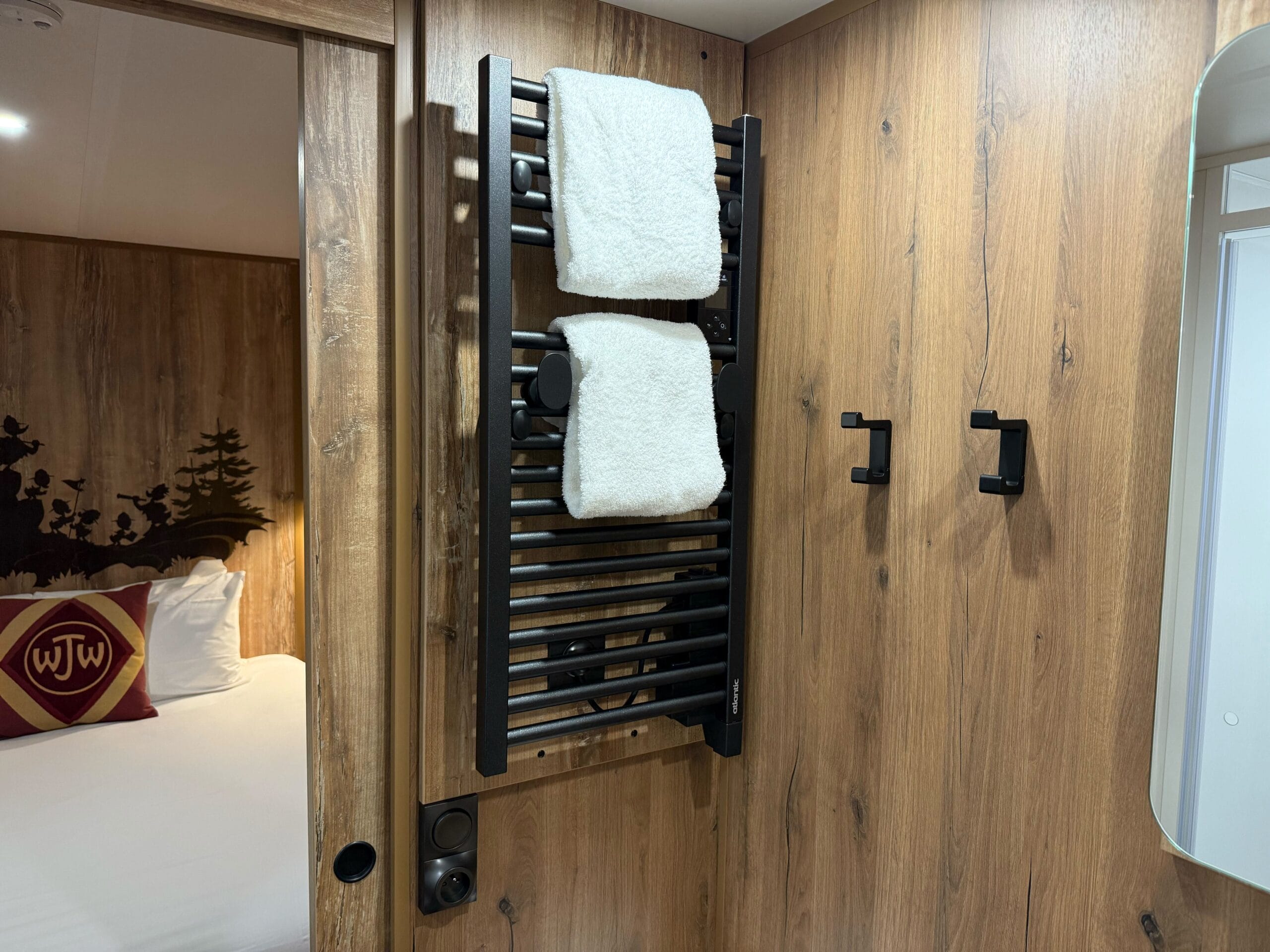 A black heated towel rack with towels in a cozy Davy Crockett Ranch Standard Cabin Room at Disneyland Paris.