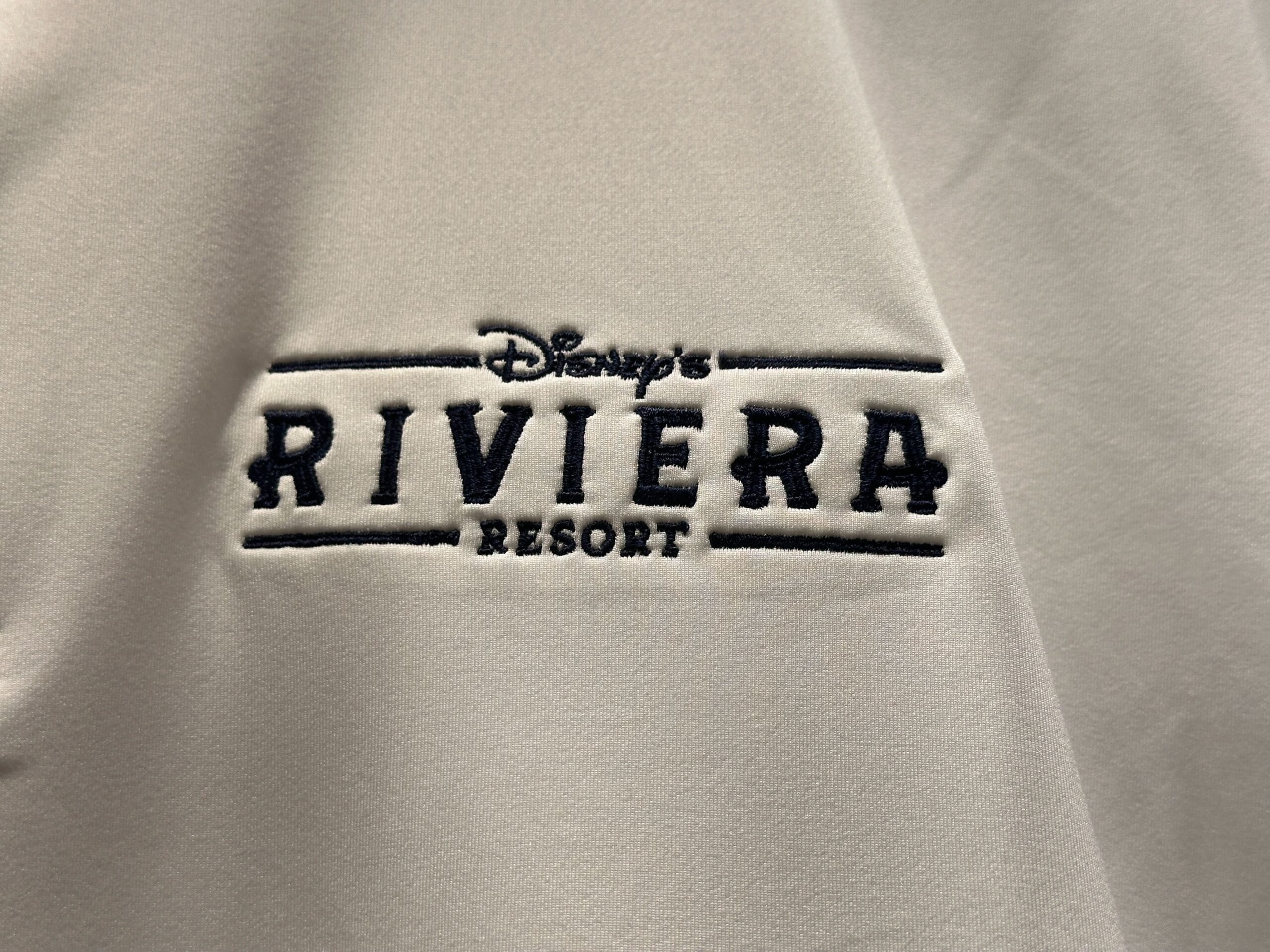 Embroidered "Disney's Riviera Resort" logo on light fabric, seen on merchandise sold at Walt Disney World Resort, no castle visible.