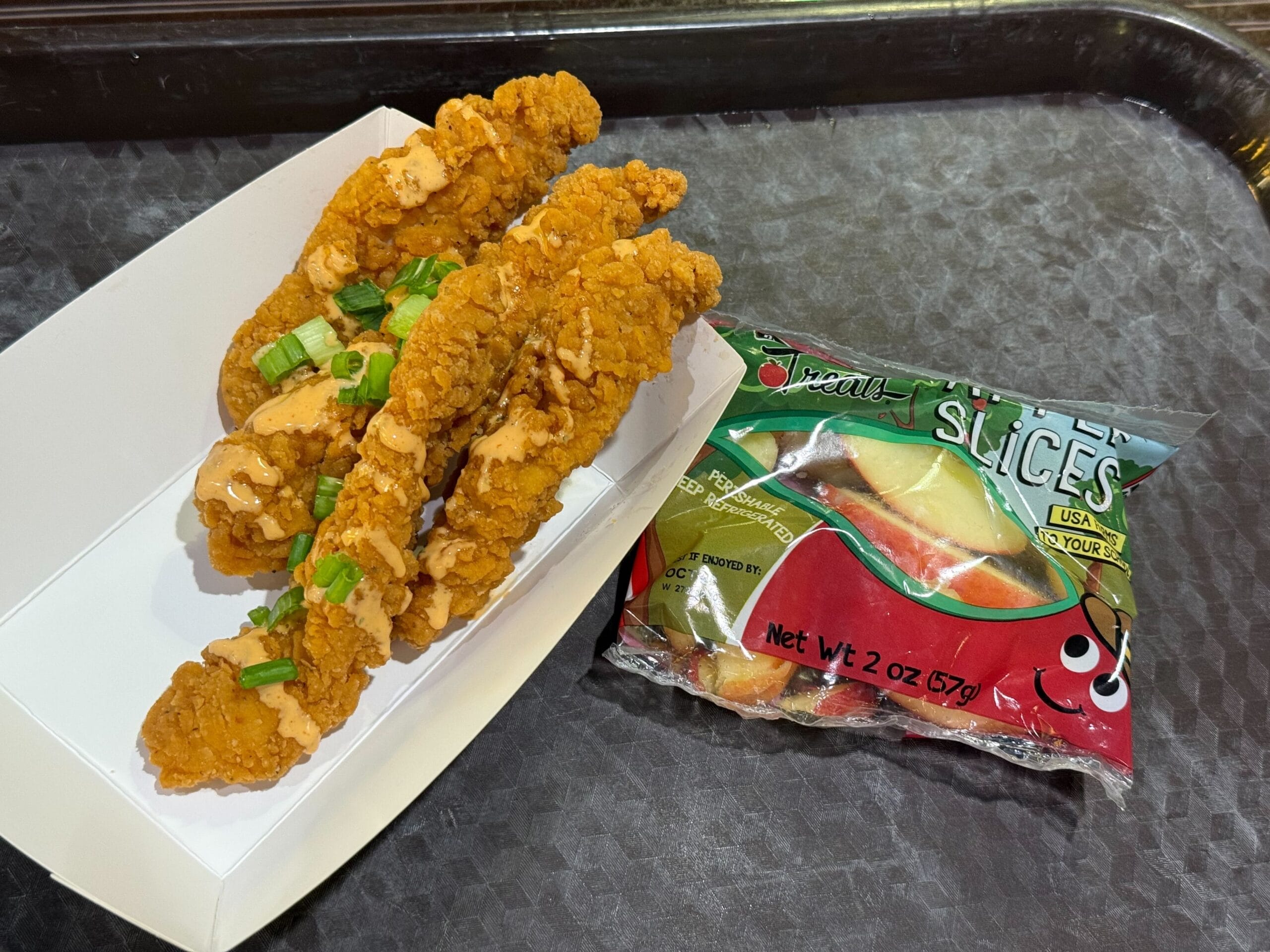Buffalo Ranch Chicken Strips with green onions and apple slices on a Magic Kingdom-style tray resembling Disney castle motifs.