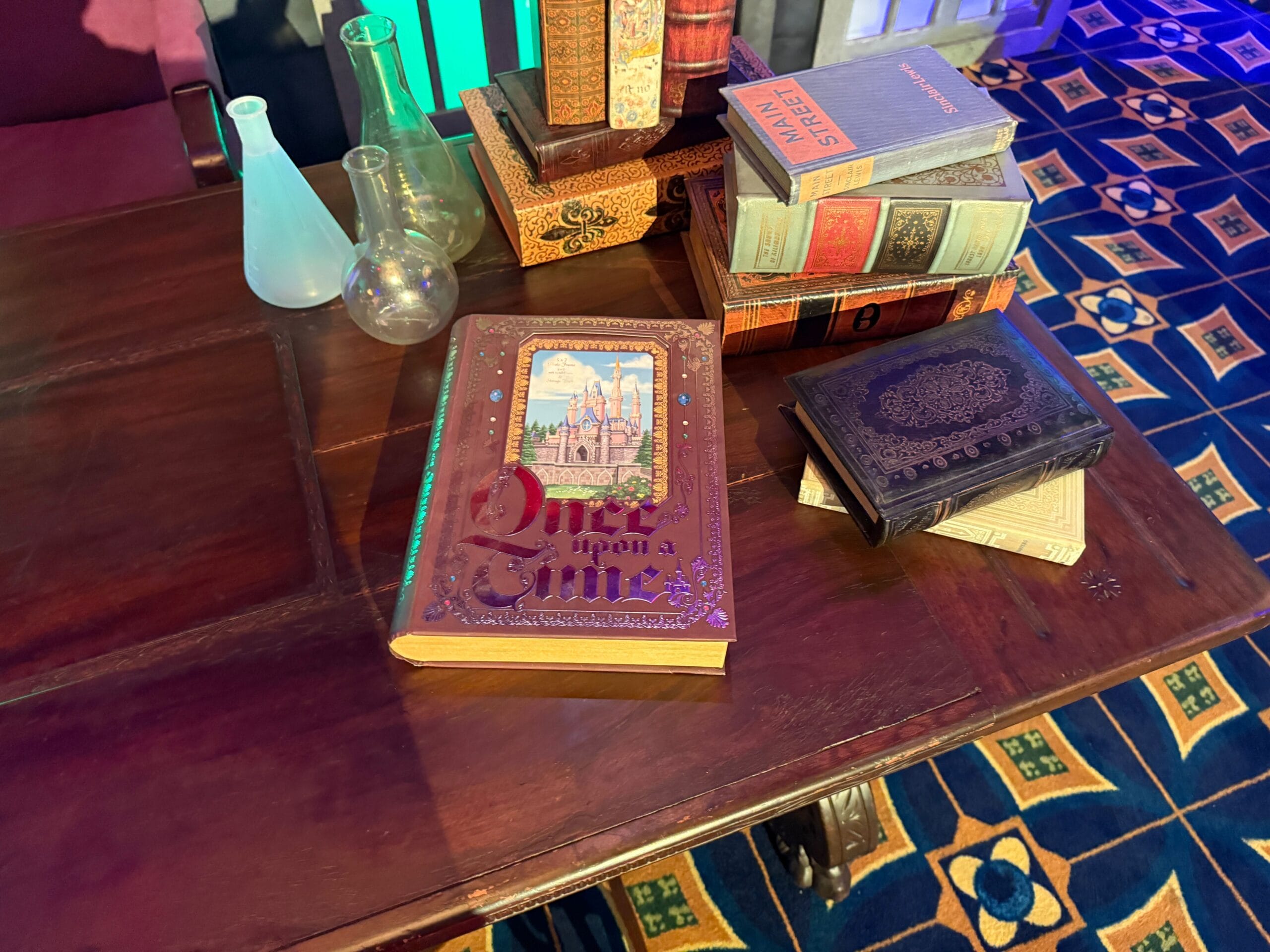 A "Once Upon a Time" book sits by an Evil Queen Mug on a wooden table at the Disneyland Hotel.