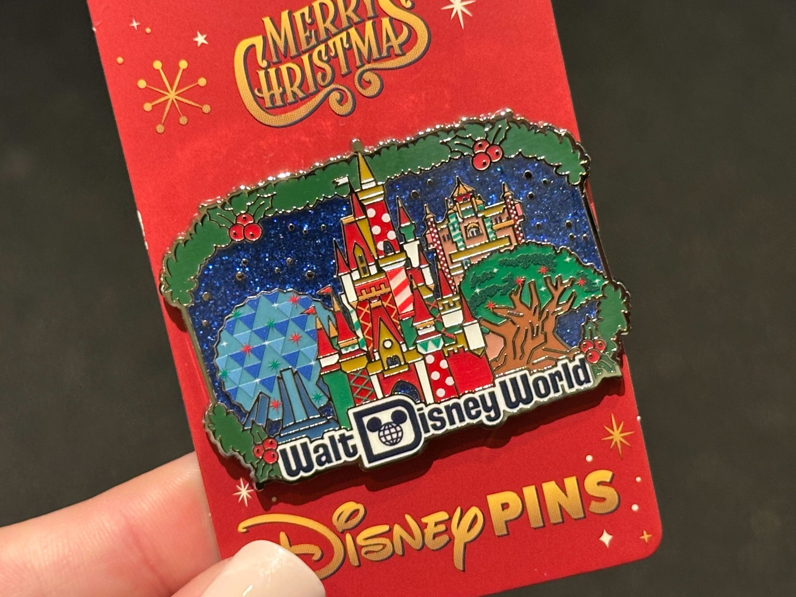A hand displays a bright 2025 Walt Disney World Christmas pin on a festive red "Merry Christmas" Disney Pins card, WDW exclusive.