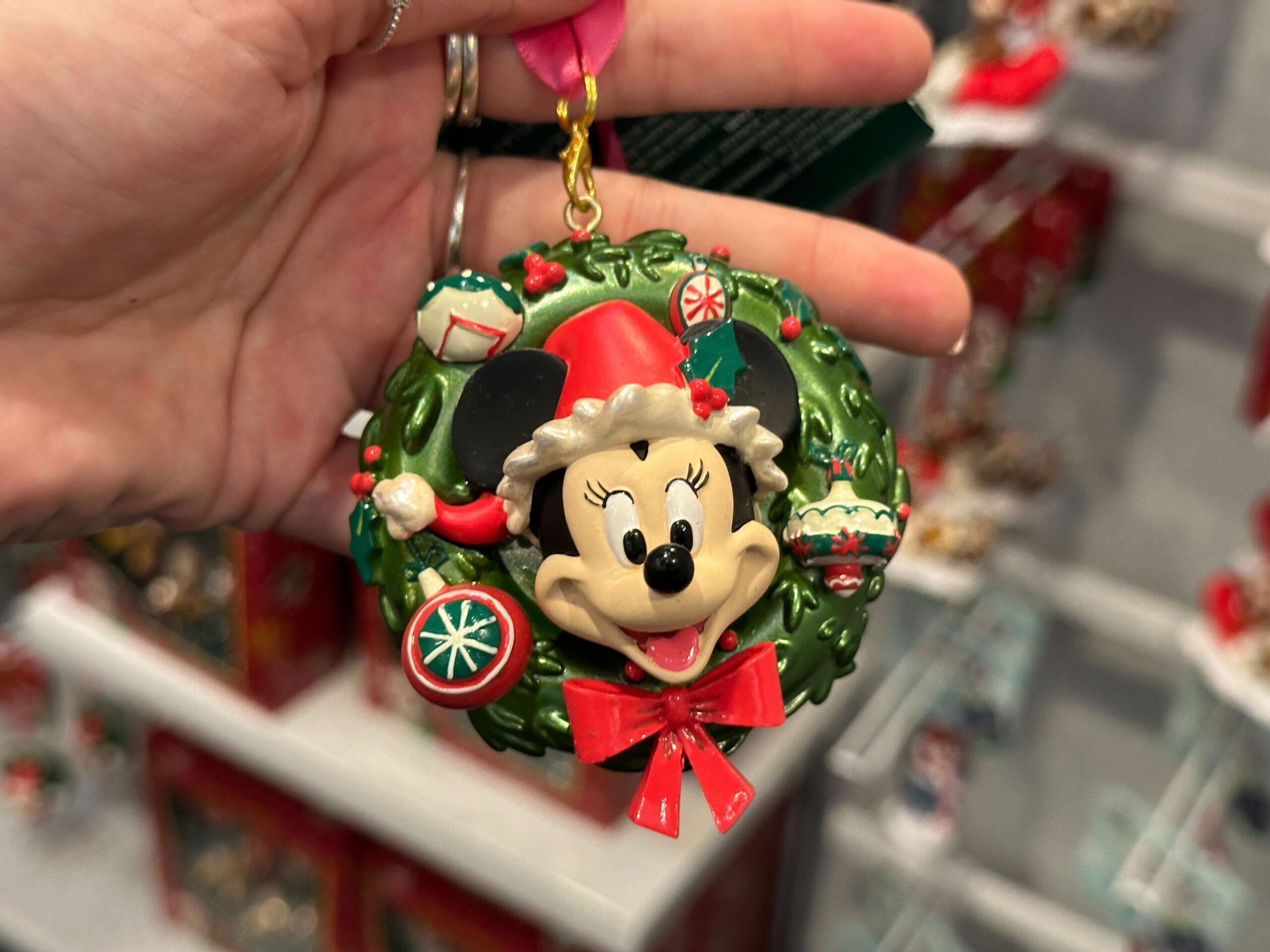 A hand displays a Walt Disney World Minnie Mouse Christmas wreath ornament, featuring holiday touches unique to Disney World's style.