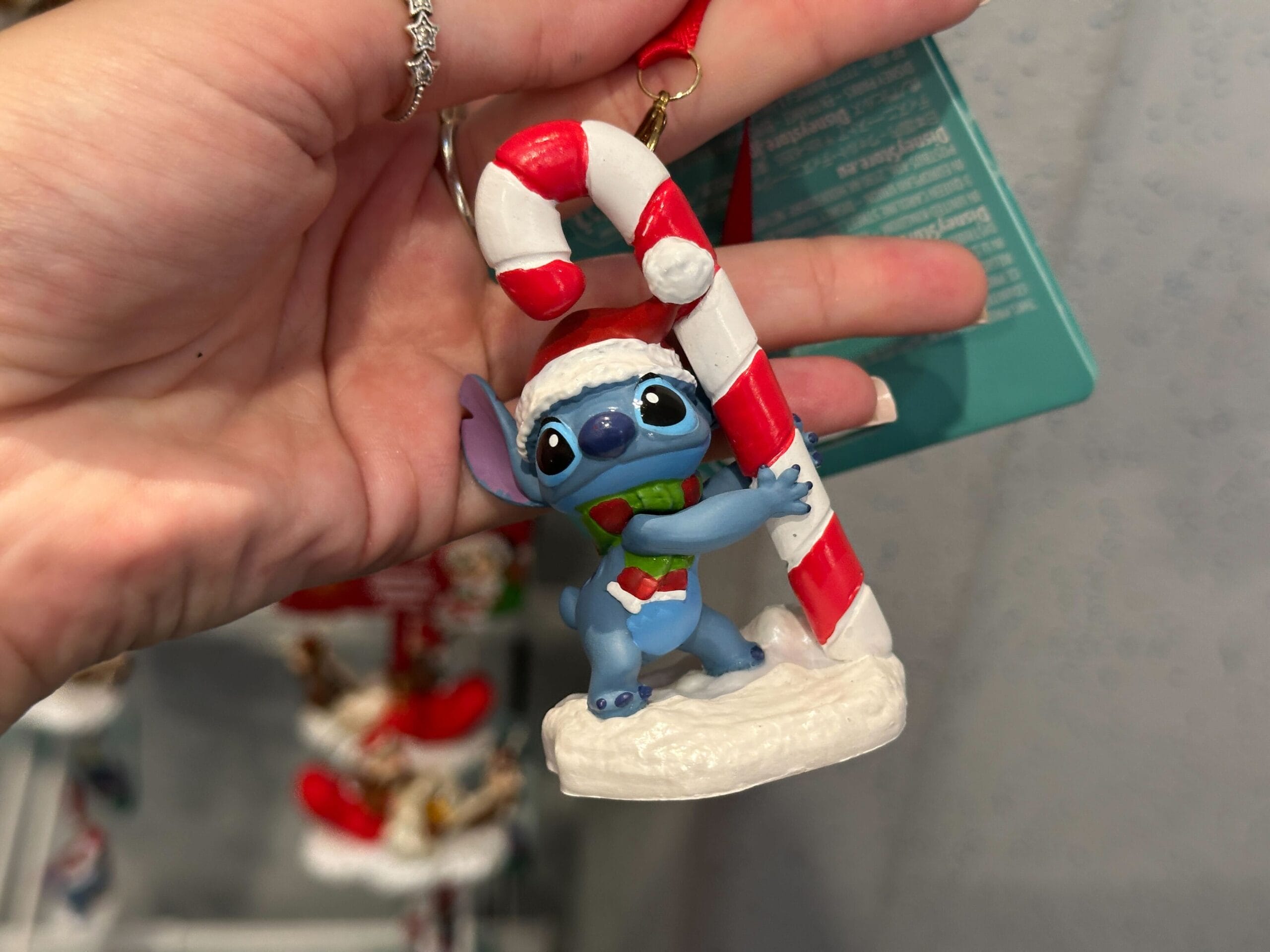 Hand holds a Stitch Christmas ornament from Walt Disney World 2025 collection—no castle, but festive merch found in the parks.
