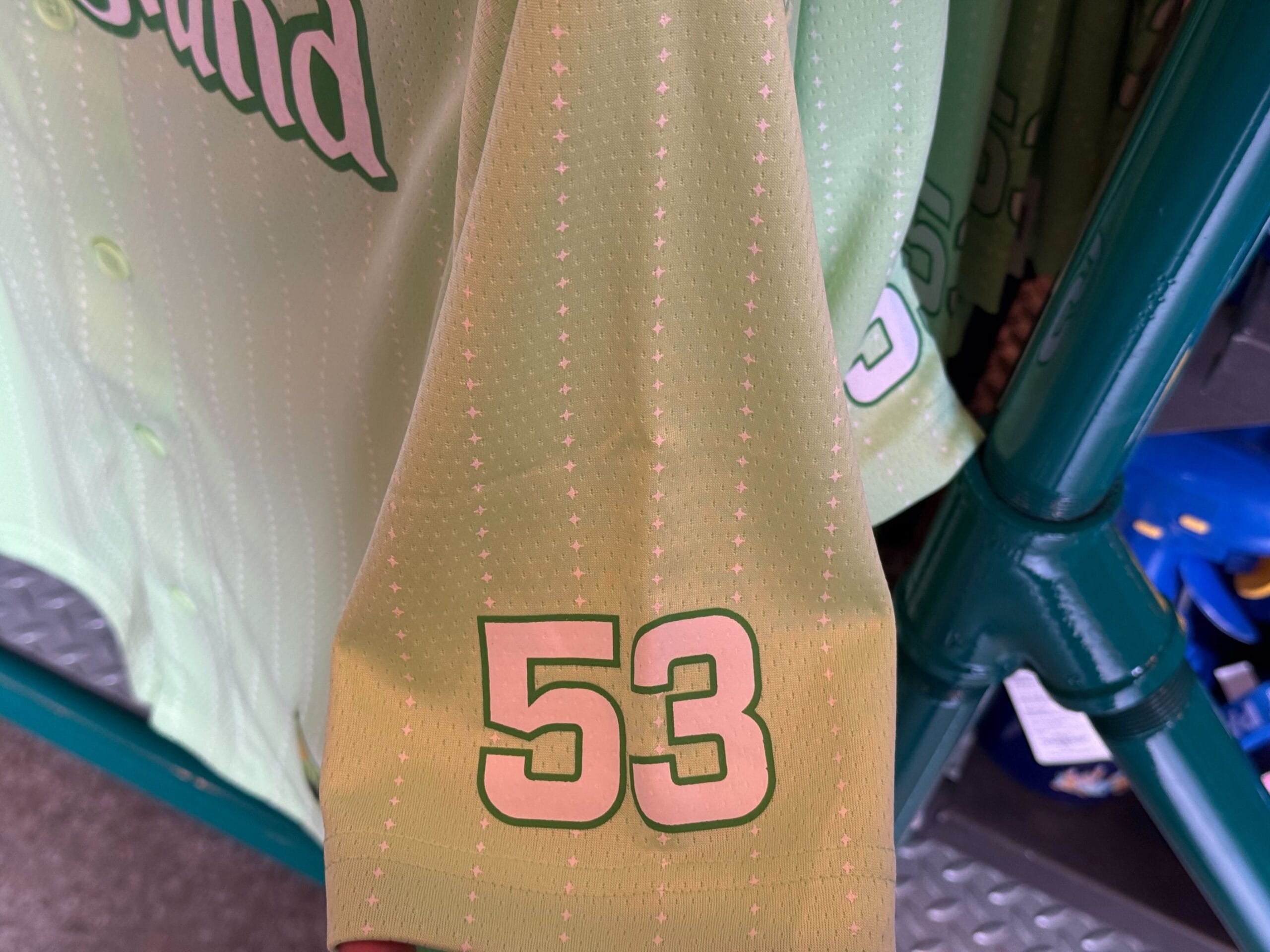 Close-up of a light green sports jersey sleeve with the number 53 printed in white and outlined in green.