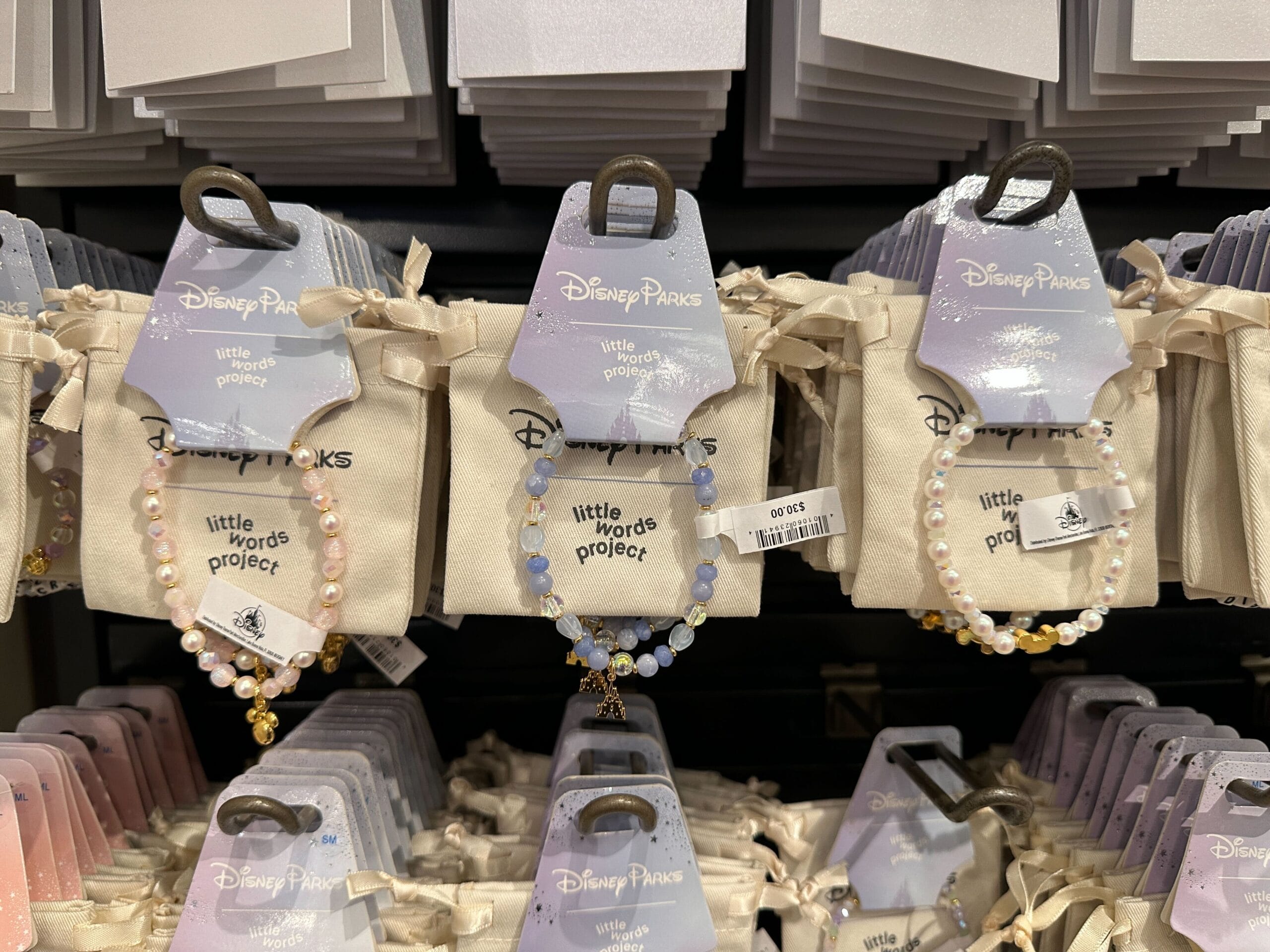 Pastel Disney Parks Little Words Project bracelets hang on display in a store.