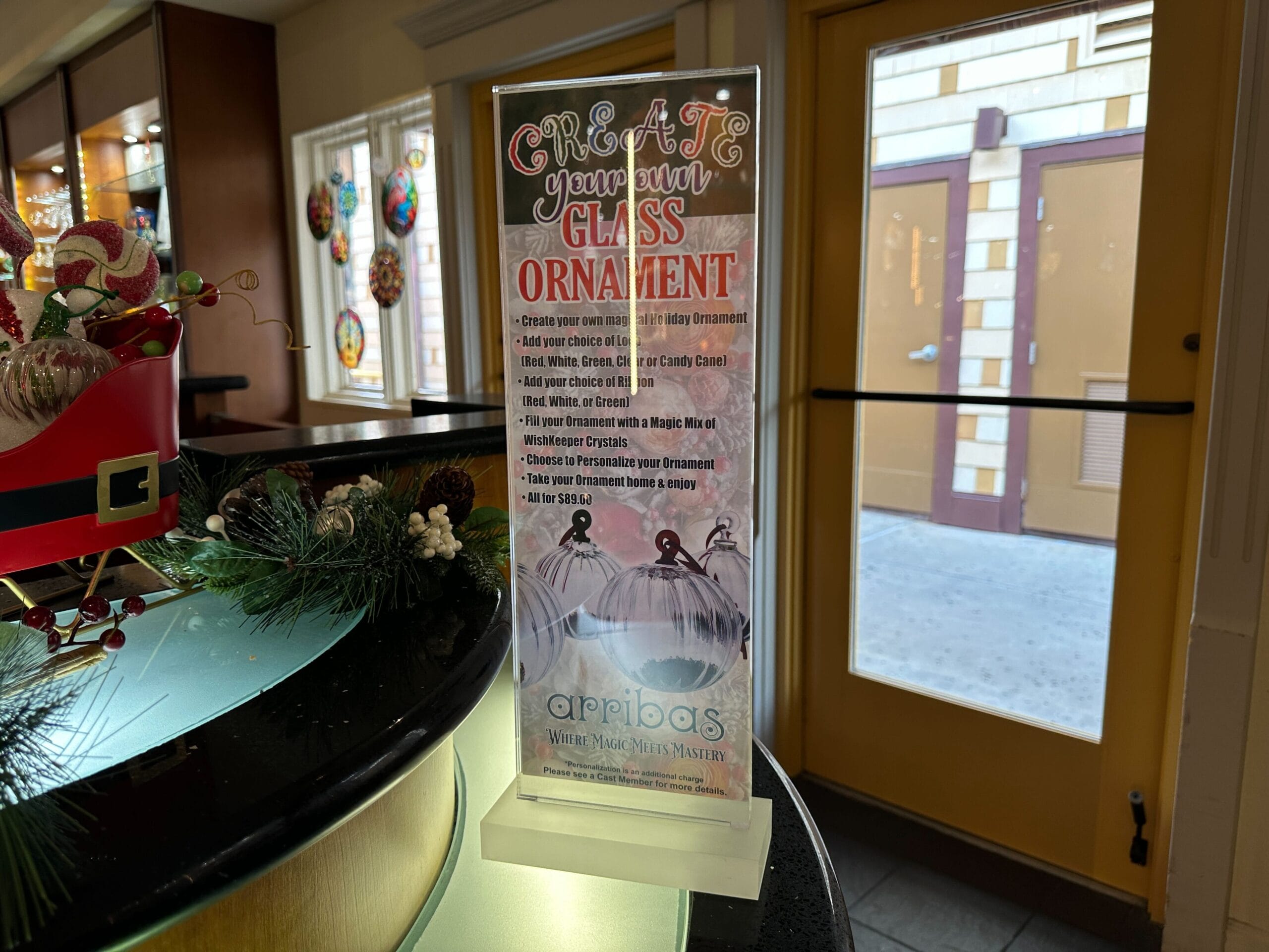 A sign on a counter advertises "Create Your Own Glass Ornament" at Crystal Arts in Walt Disney World.