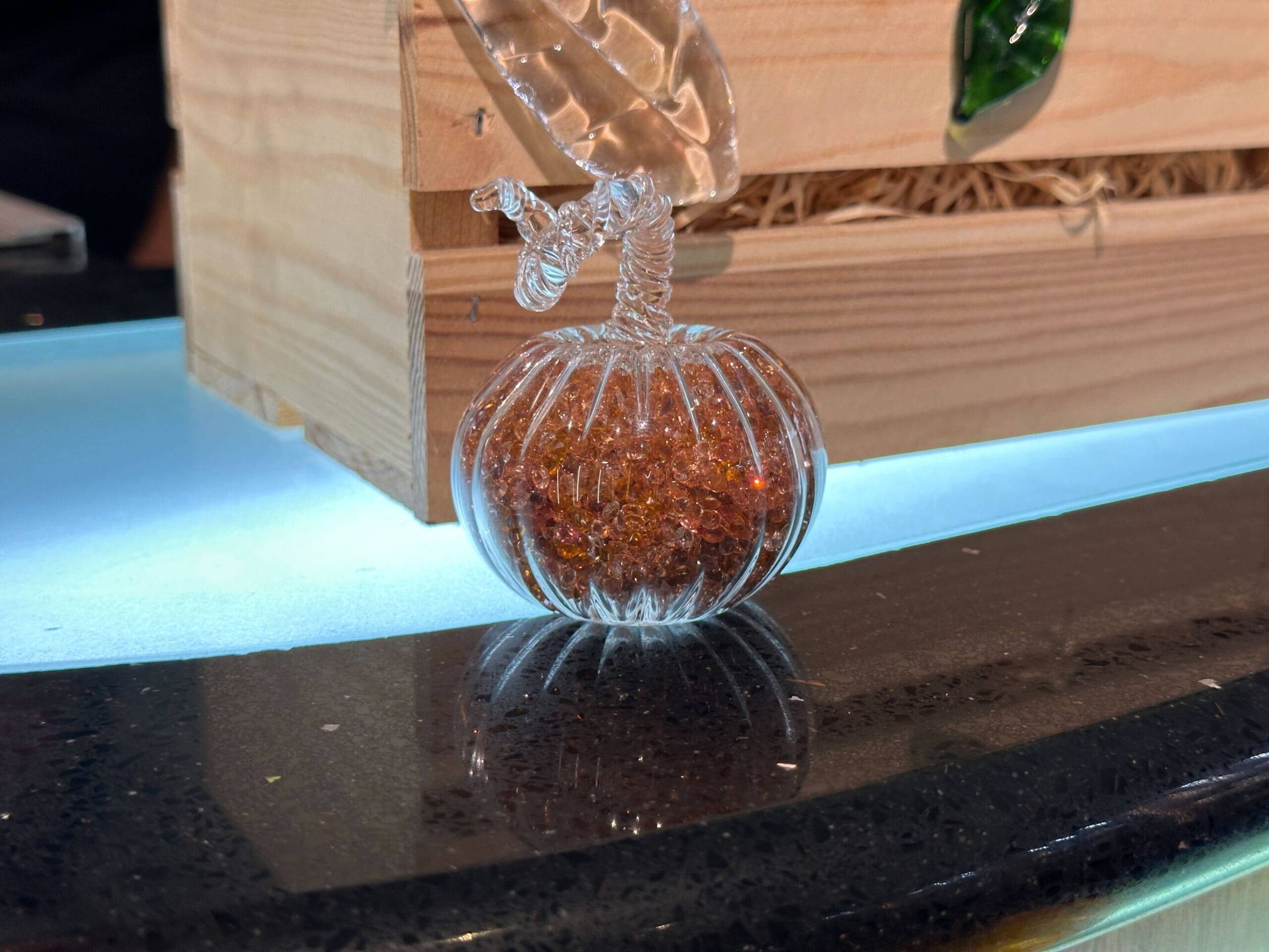 A glass pumpkin filled with orange crystals sits on a counter at Crystal Arts in Walt Disney World.